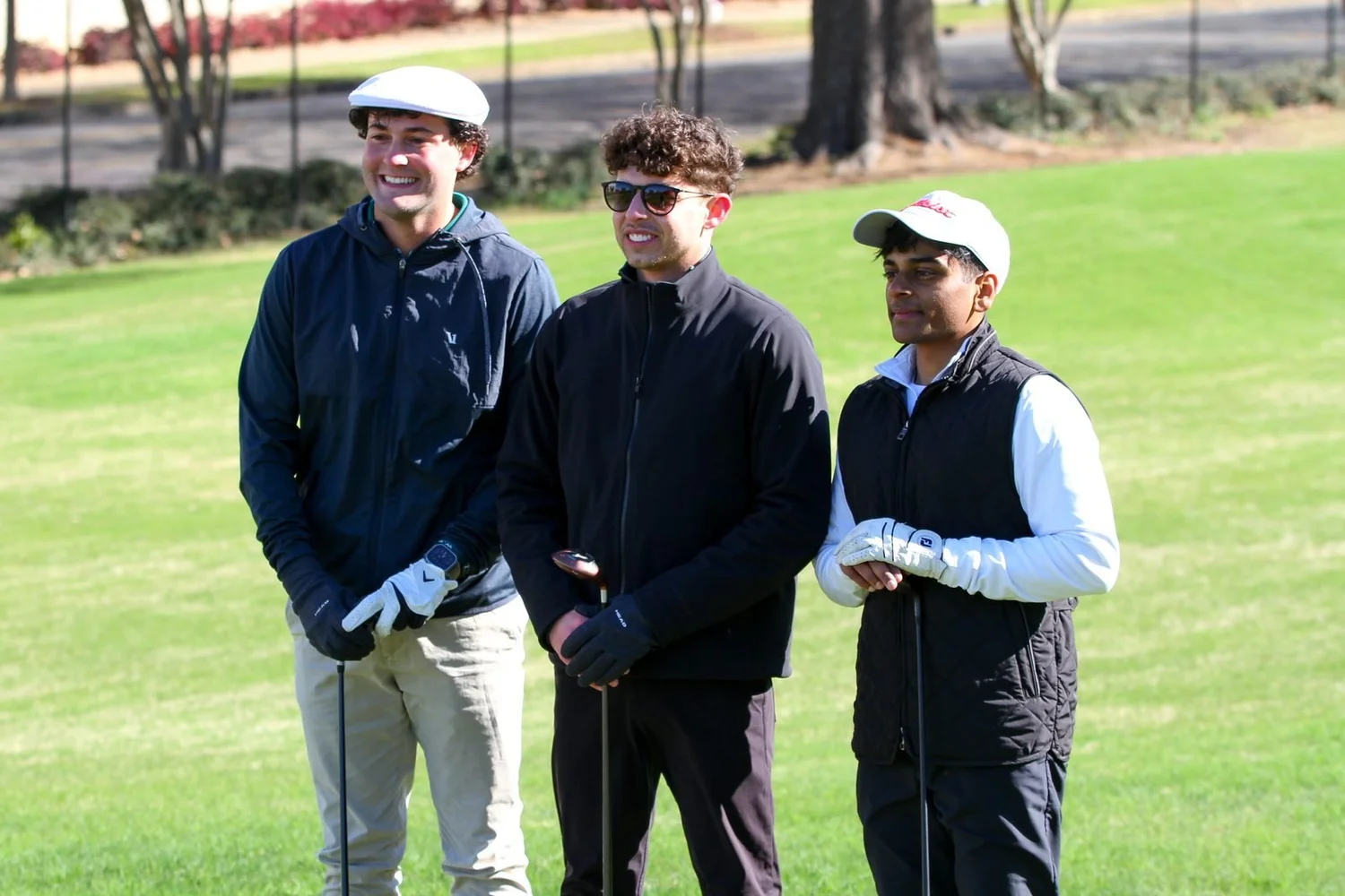 Three golfers waiting on the tee box