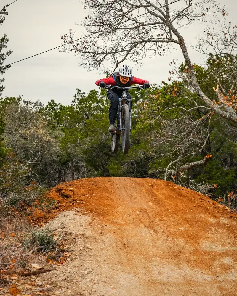 Rider in the air over a red-dirt jump during a THCMTB session
