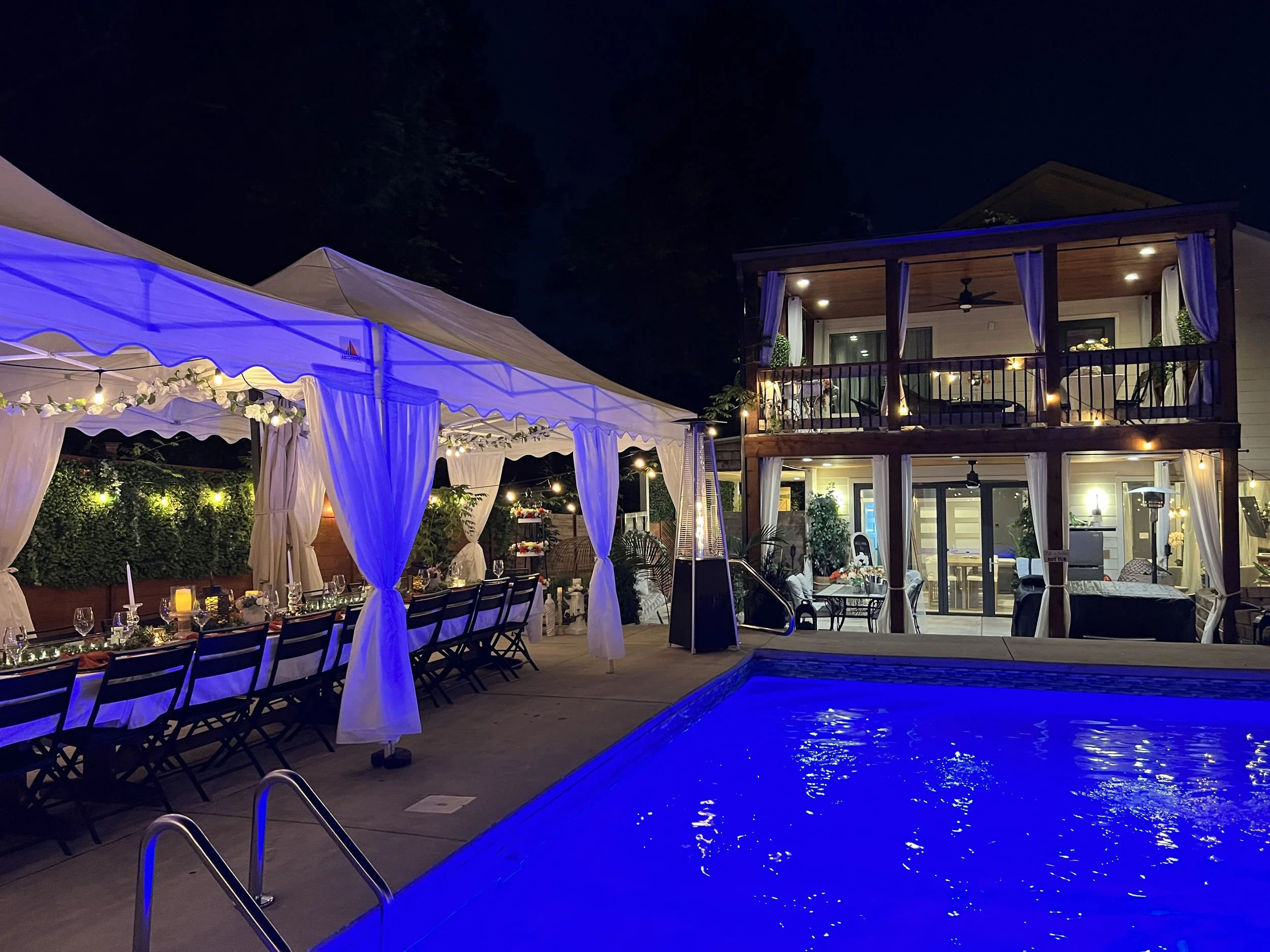 Pool lit blue at night beside the tented table