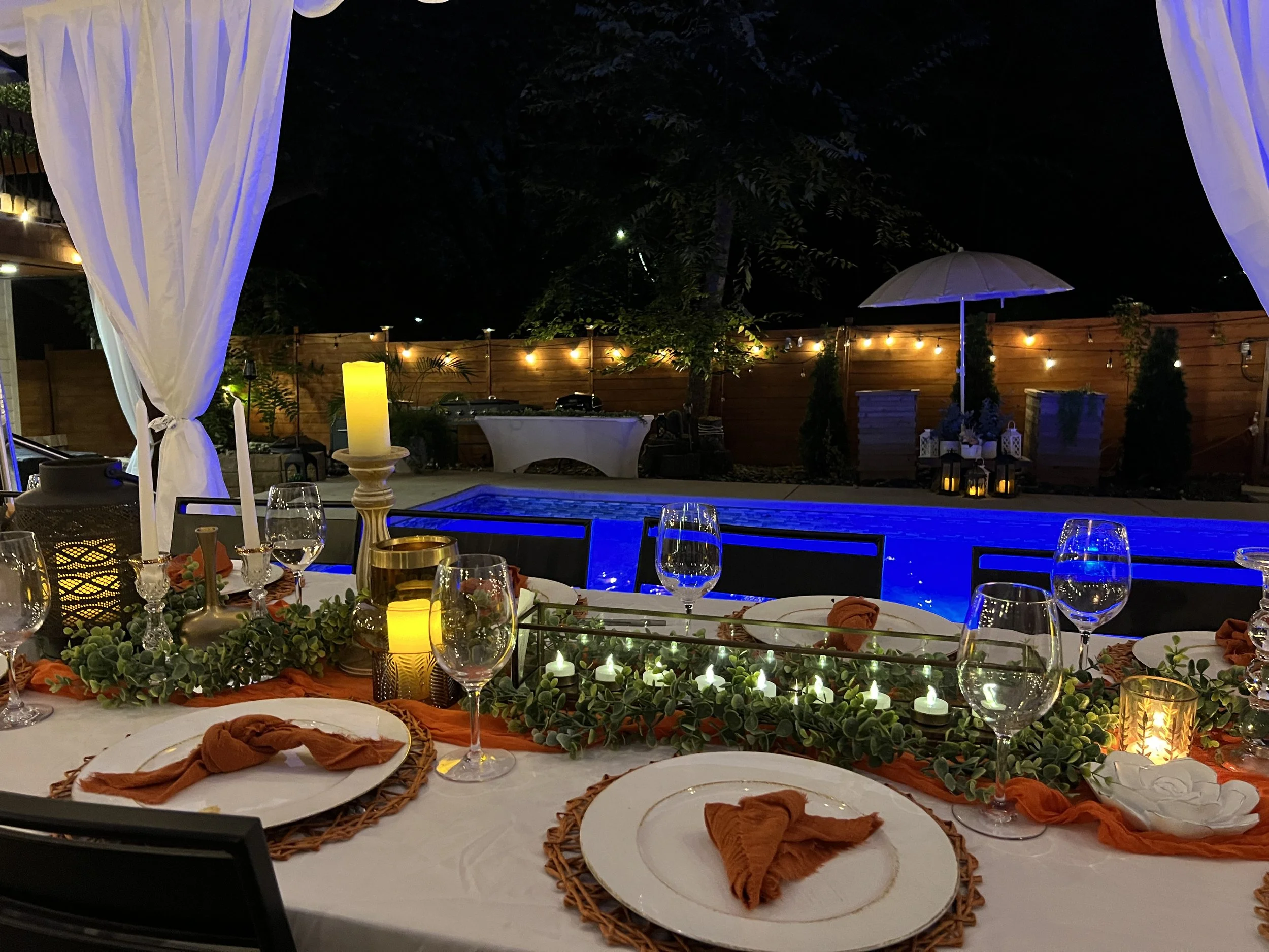 Candlelit place setting at night with the pool glowing behind it
