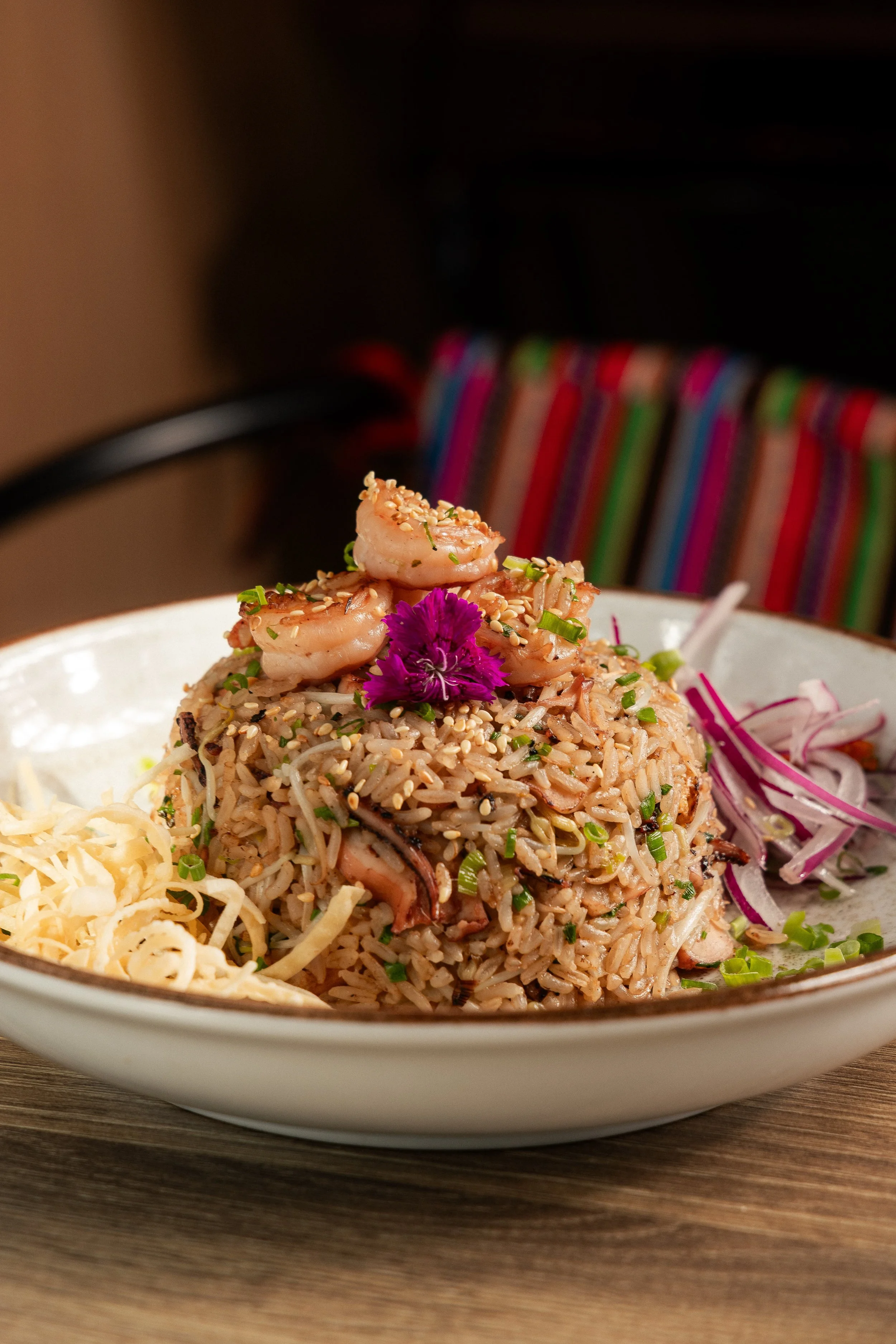 Enkai fried rice topped with shrimp, red onion and an edible flower.