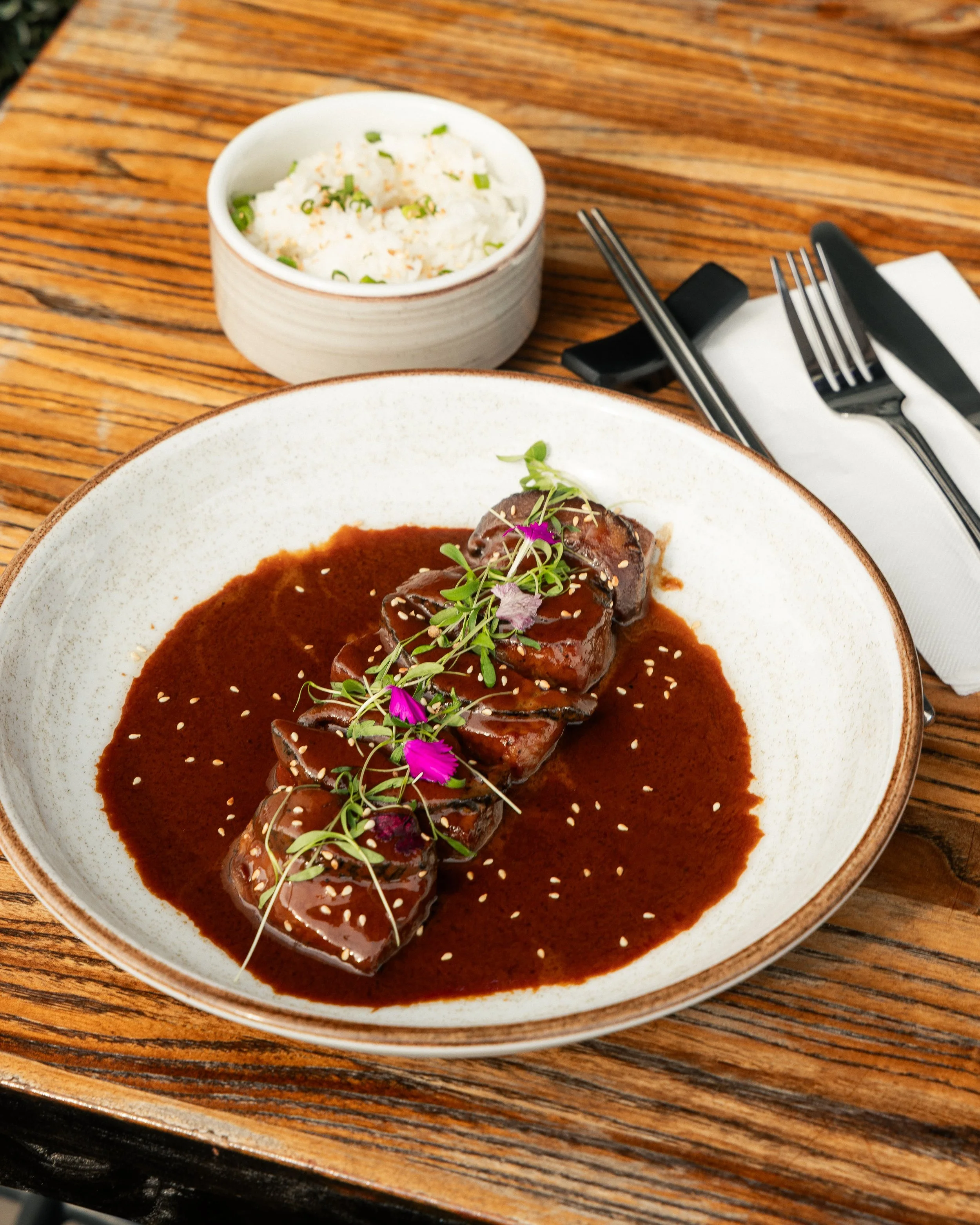 Enkai beef entrée with dark sauce, microgreens and edible flowers.