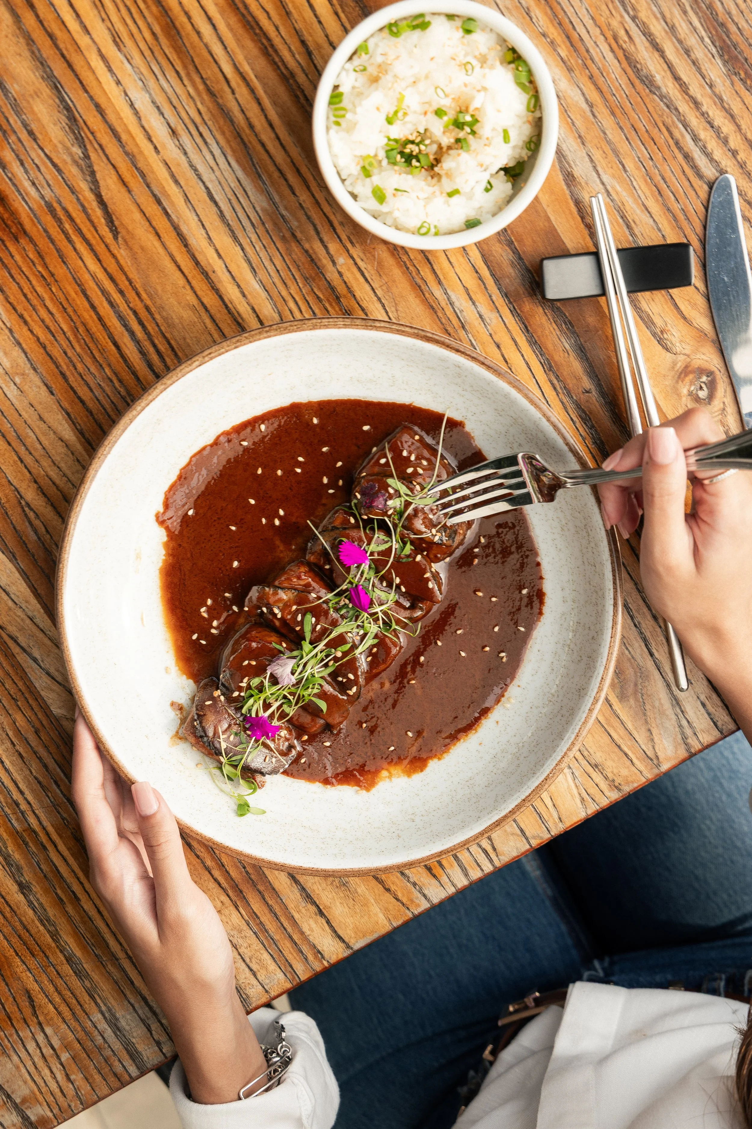 Overhead view of an Enkai beef entrée in dark sauce with edible flowers.