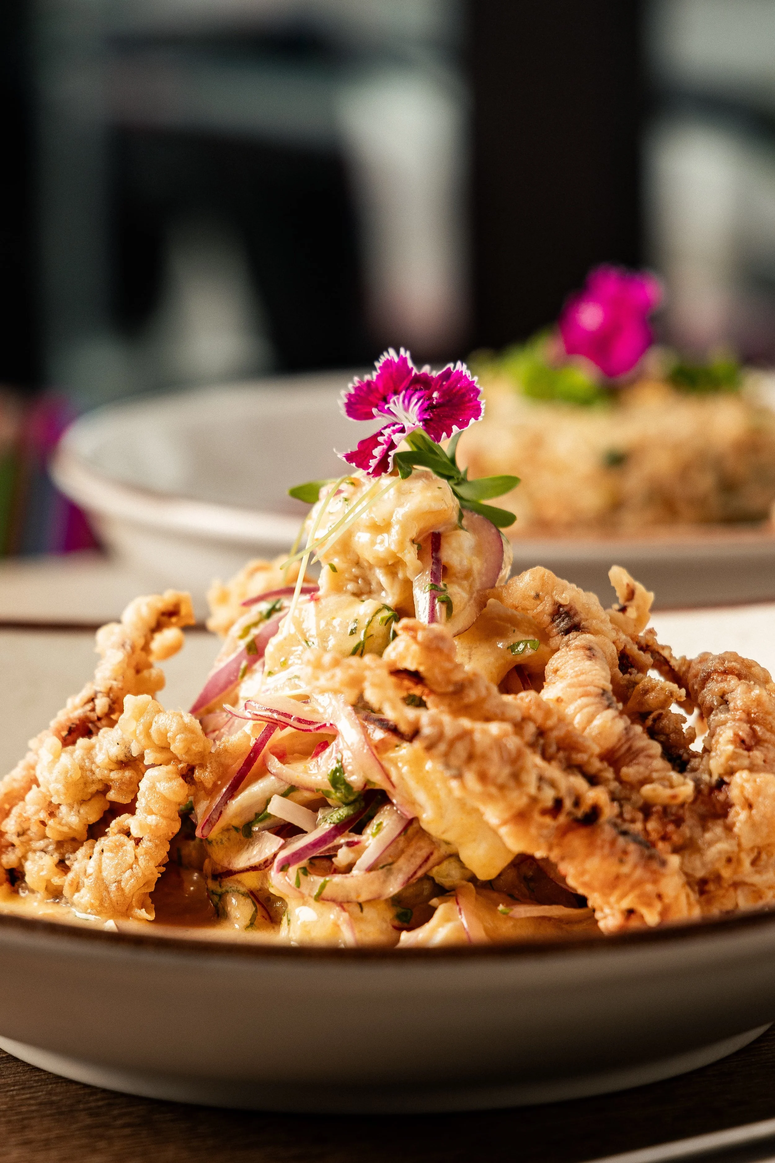 Crispy seafood dish with red onion, edible flowers and creamy sauce at Enkai.