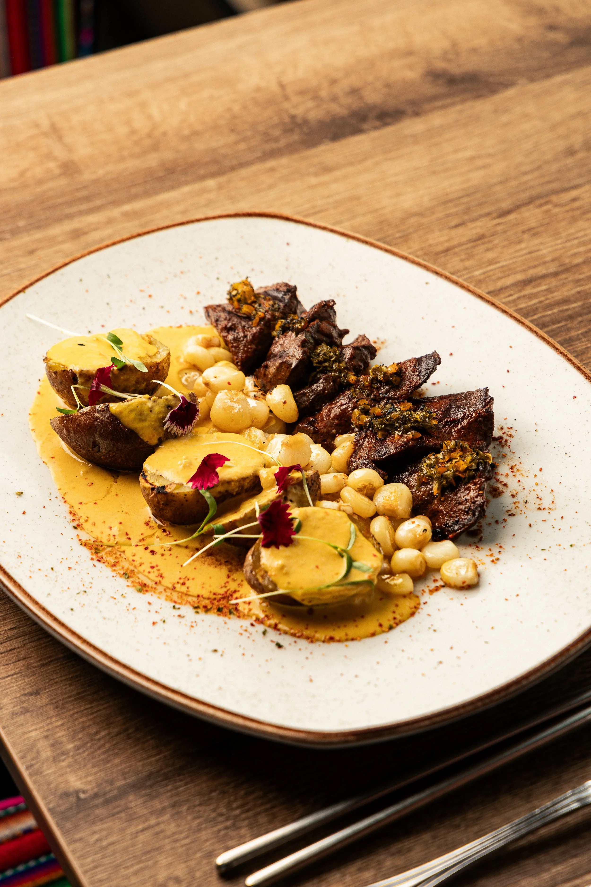 Grilled meat with yellow potatoes, corn and creamy sauce at Enkai.