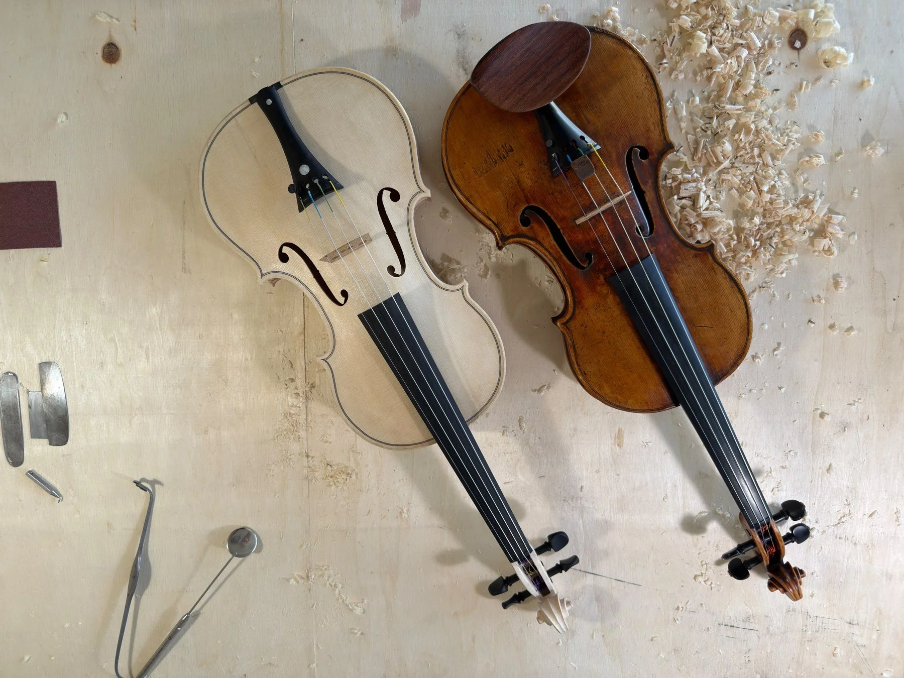 The unvarnished copy on the left and Nelli Shkolnikova’s original violin on the right, on the luthiers’ workbench