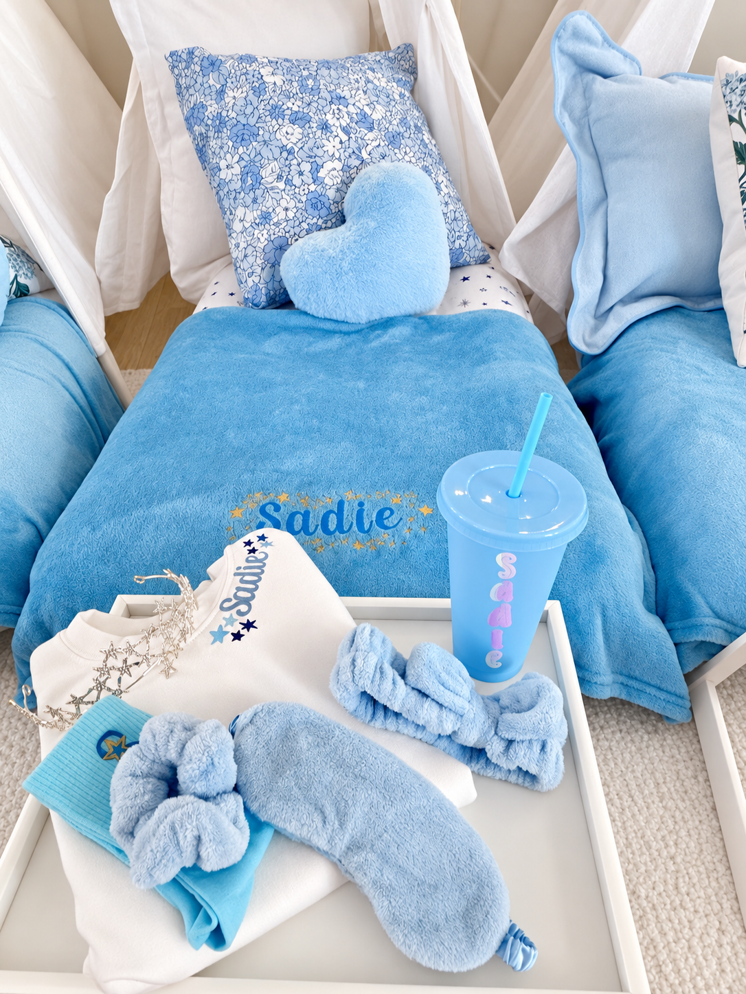 A soft blue blanket embroidered with Sadie’s name and gold stars in a coordinated sleepover setting