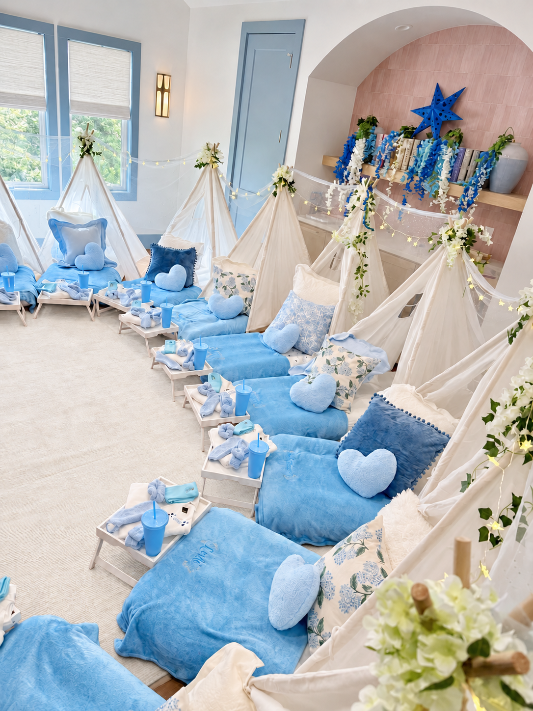 A blue sleepover setting with white tents, soft blankets, and personalized guest details