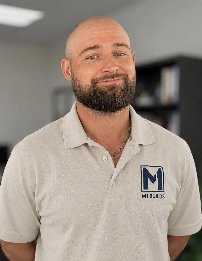 Man, shaved head, full beard, M1 Builds, tan polo shirt, office, professional, construction, builder