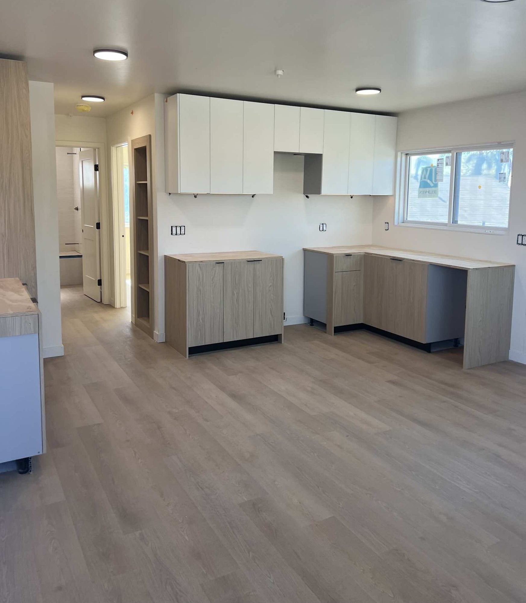 Finished kitchen with white upper cabinets and plank flooring