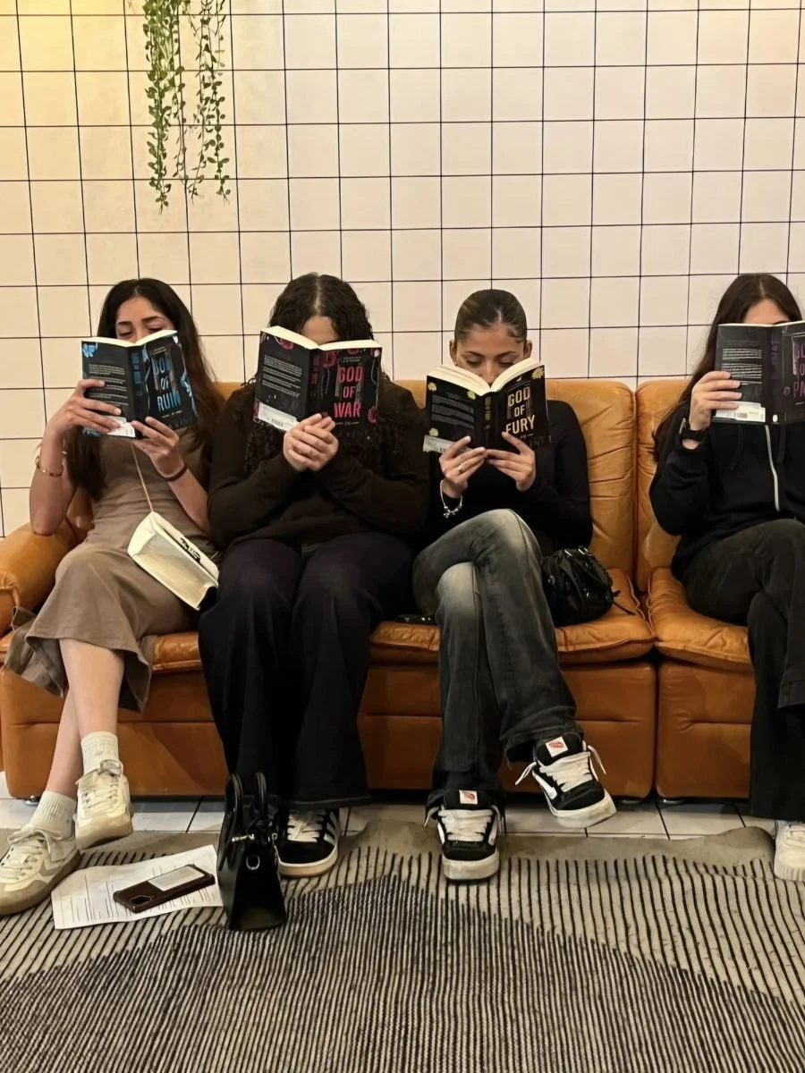 Vier leerlingen lezen in de zetel, hun boek voor het gezicht