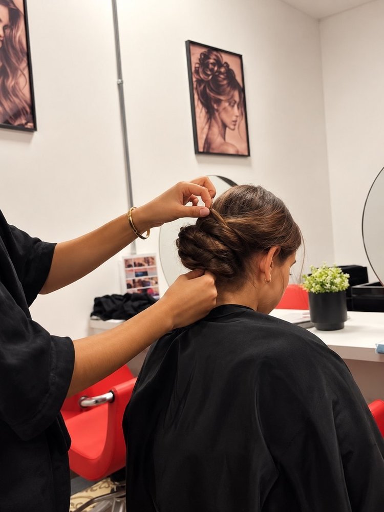 Een leerling Haarzorg steekt het haar van een klant op