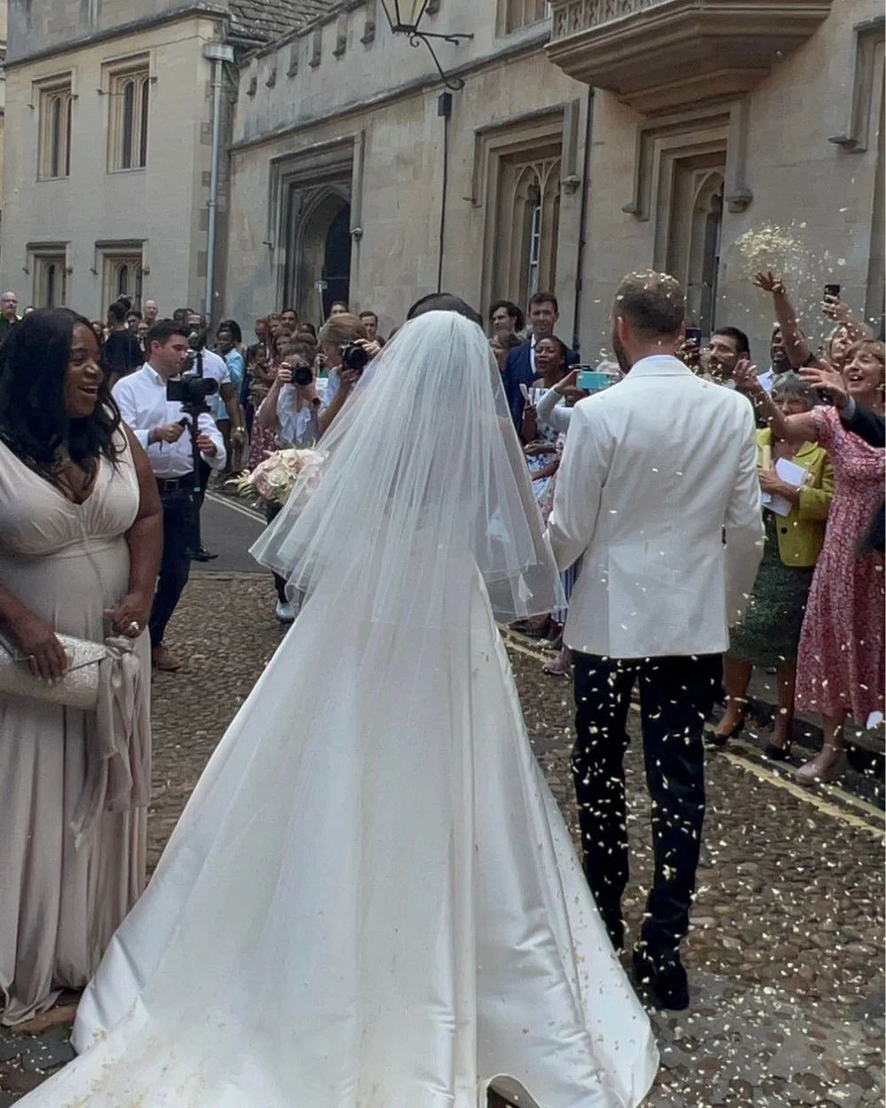 Ben and Colleen walking through confetti and cheering guests, photographed from a guest’s viewpoint.
