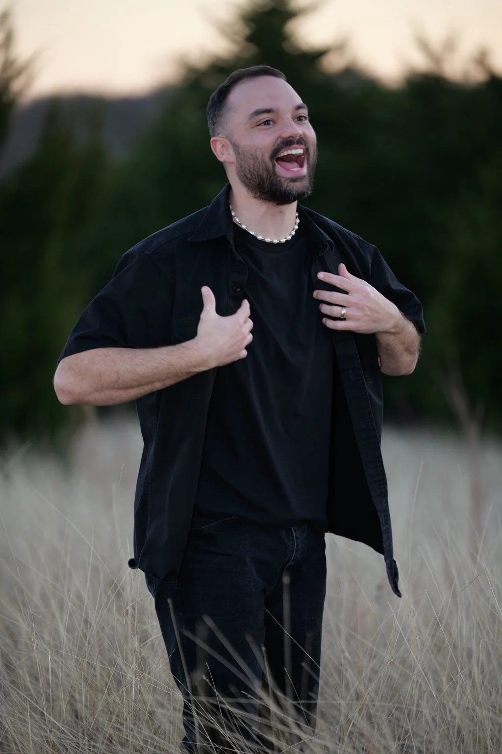 Seth Hyper Fenton smiling and gesturing in a black shirt