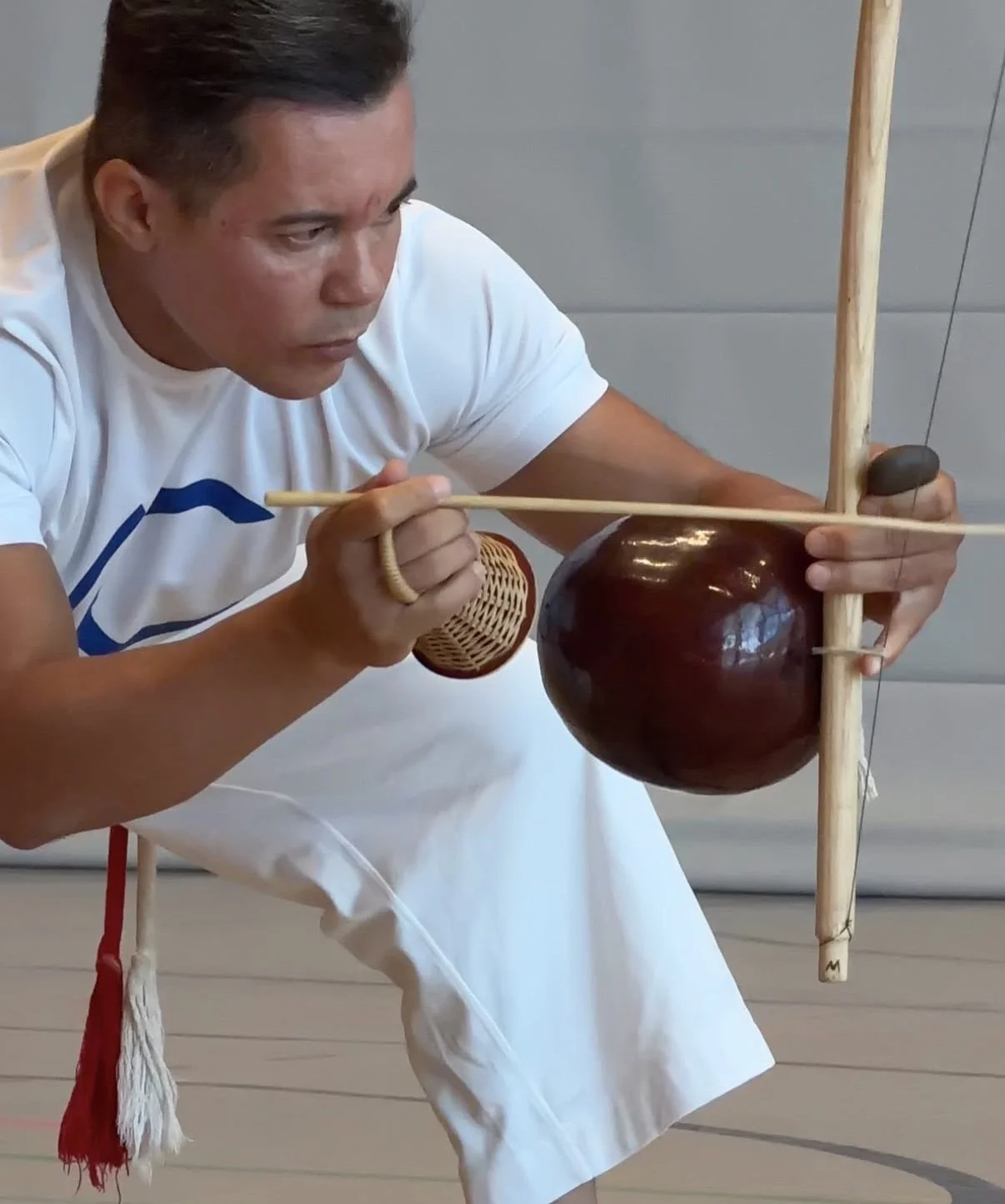 Ein Capoeirista spielt das Berimbau mit Spielstab, Stein und Caxixi-Rassel.