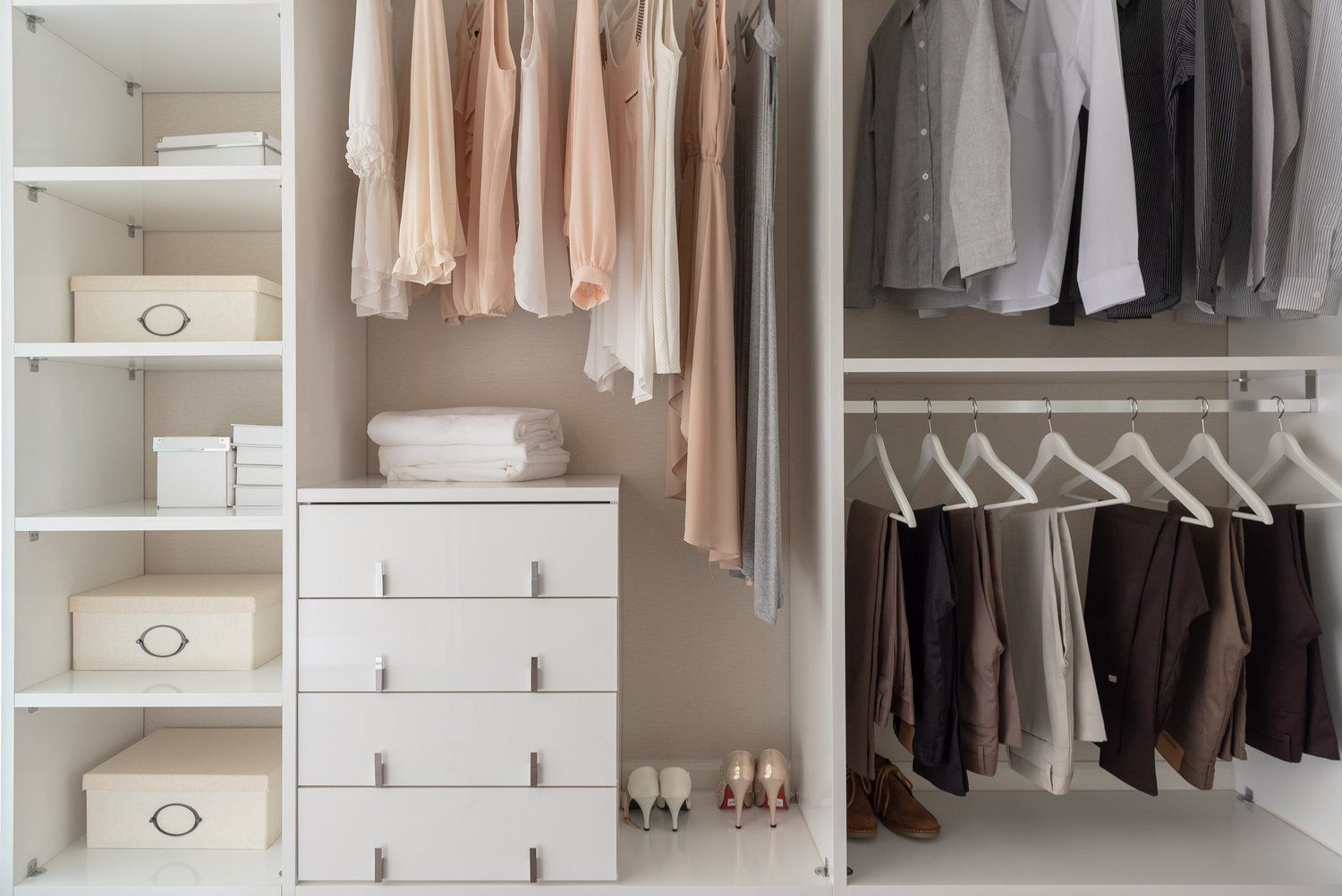 An organized closet with neatly hung clothes, lidded storage boxes and plenty of open space