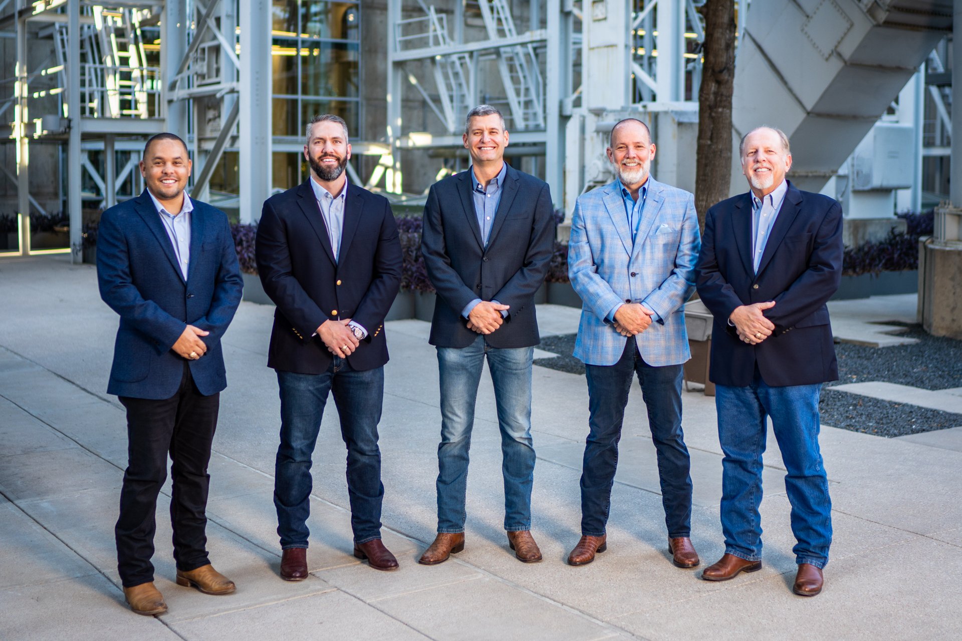 Photo of the five principals of CPM—Christian Dowell, Andrew Stauch, John Duke, Joe Tracy, and Dave Stauch—standing outdoors in business attire, representing leadership in construction project management.