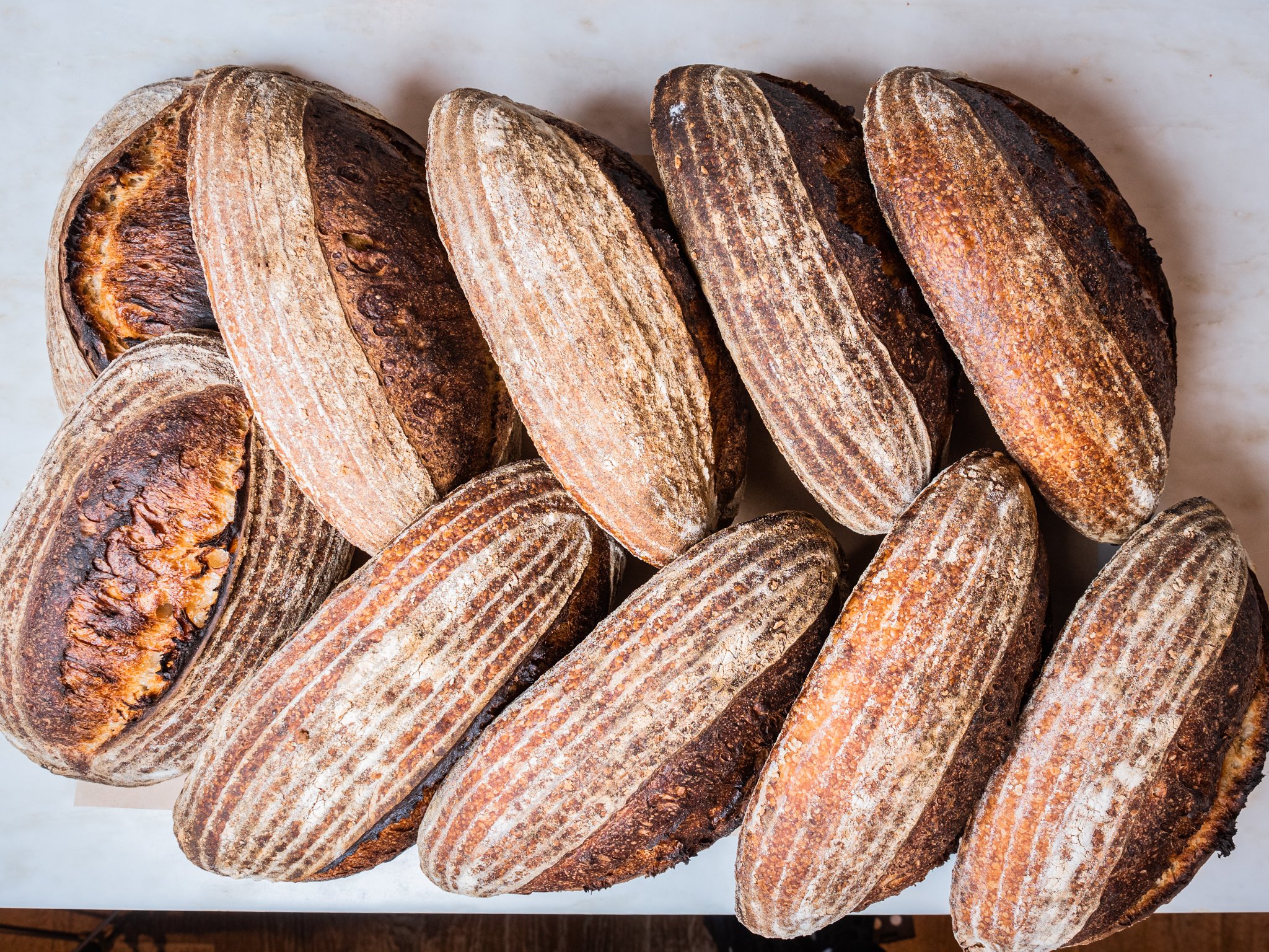 An assortment of naturally leavened sourdough breads displayed on a wooden table.