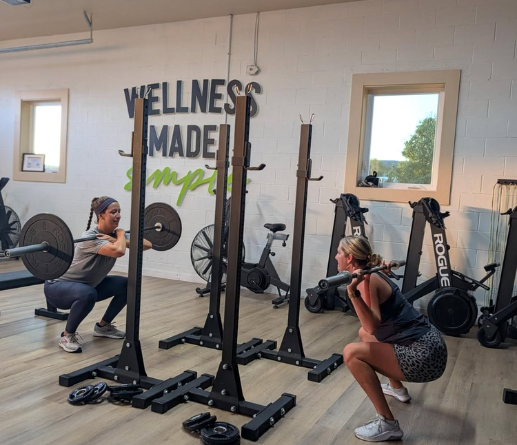 Two women strength training with barbells at SoDel Well