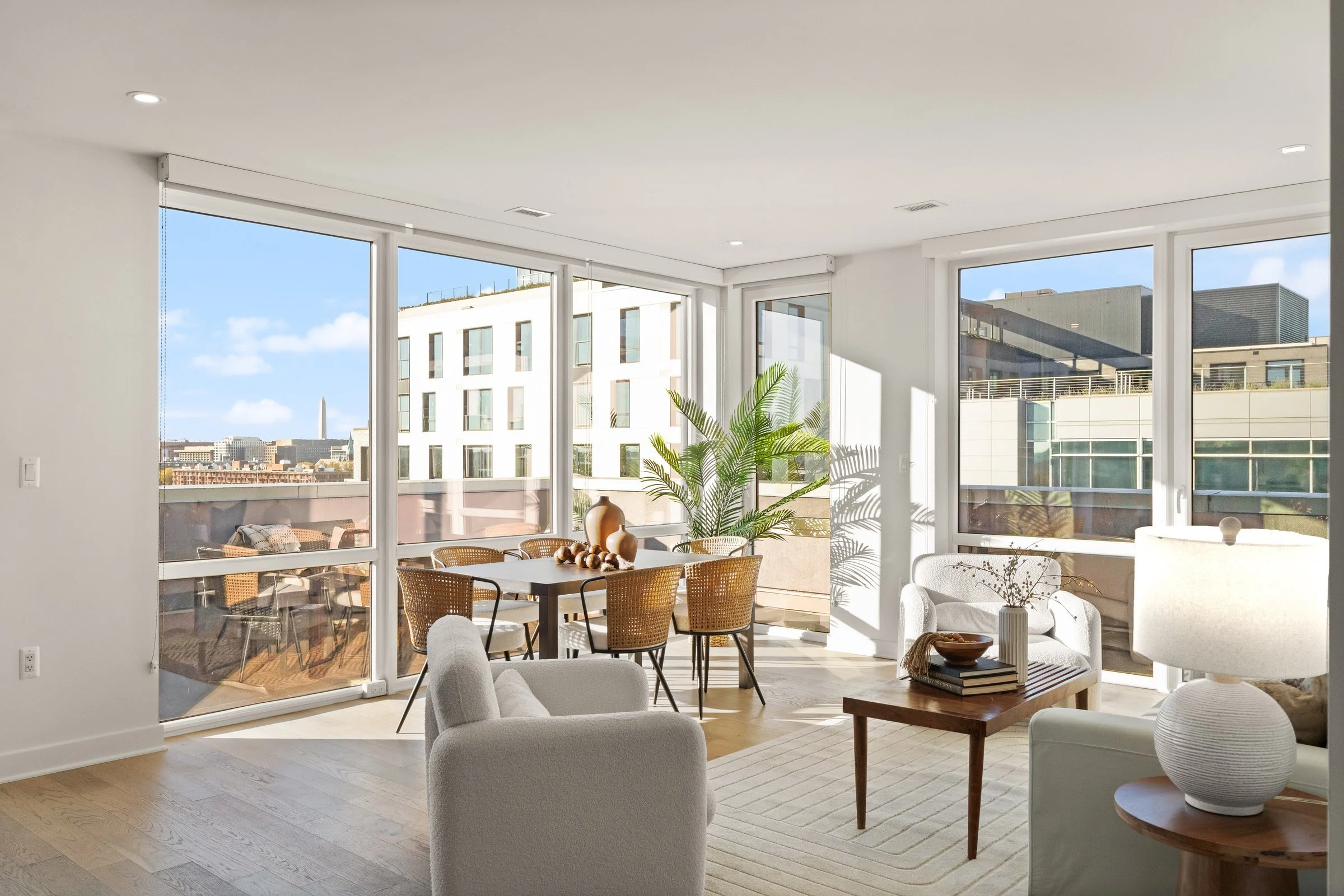 Sunlit living and dining room with floor-to-ceiling windows and a view of the Washington Monument, sold by FORWARD at Corcoran McEnearney, 37 L Street SE, Washington, DC
