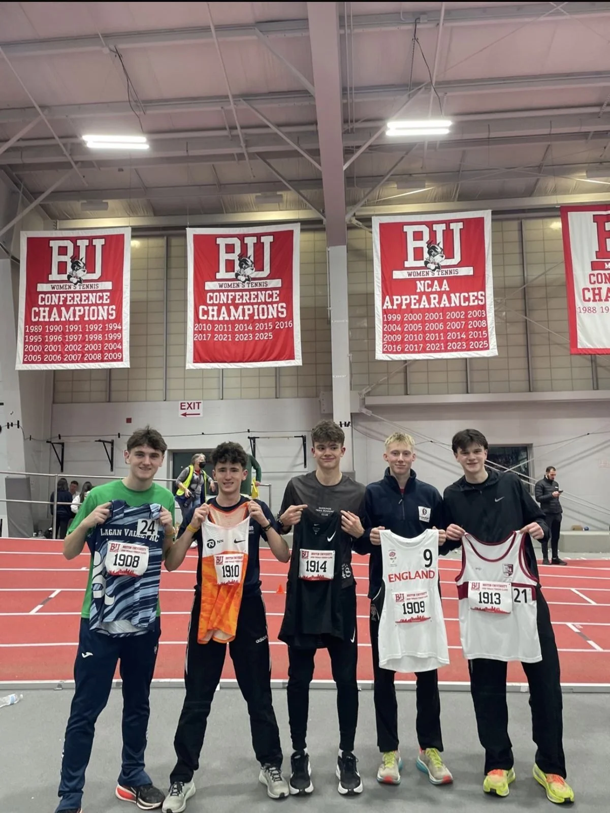 Athletes holding their race vests under the Boston University championship banners
