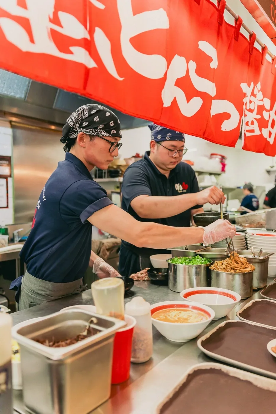 Chefs plating ramen on the line