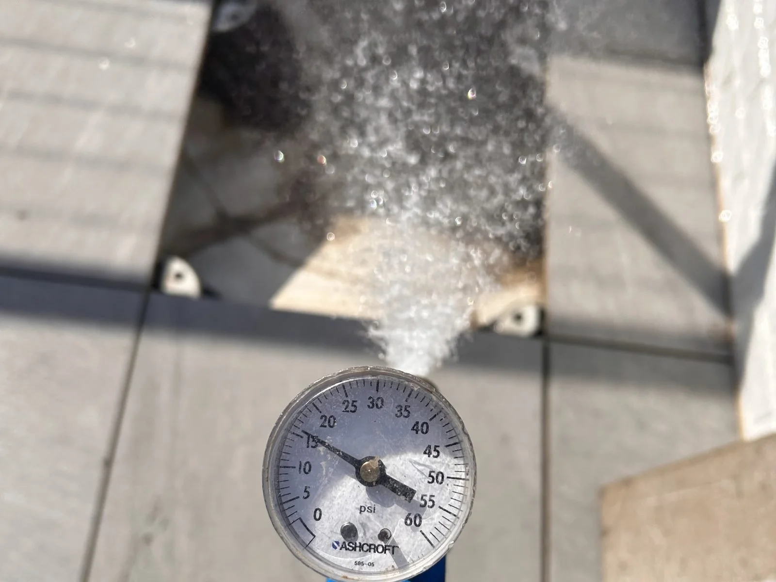Spray nozzle and pressure gauge isolating a single test area during an ASTM water test