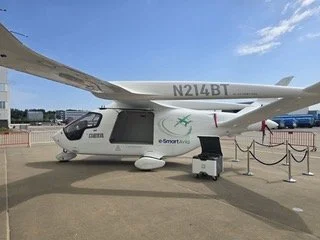 Side view of the e-Smart branded BETA ALIA aircraft, registration N214BT, with a ground unit connected.