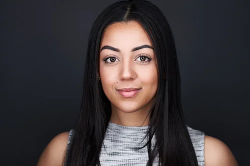 Headshot of a woman with long dark hair against a dark backdrop, ATX Headshots