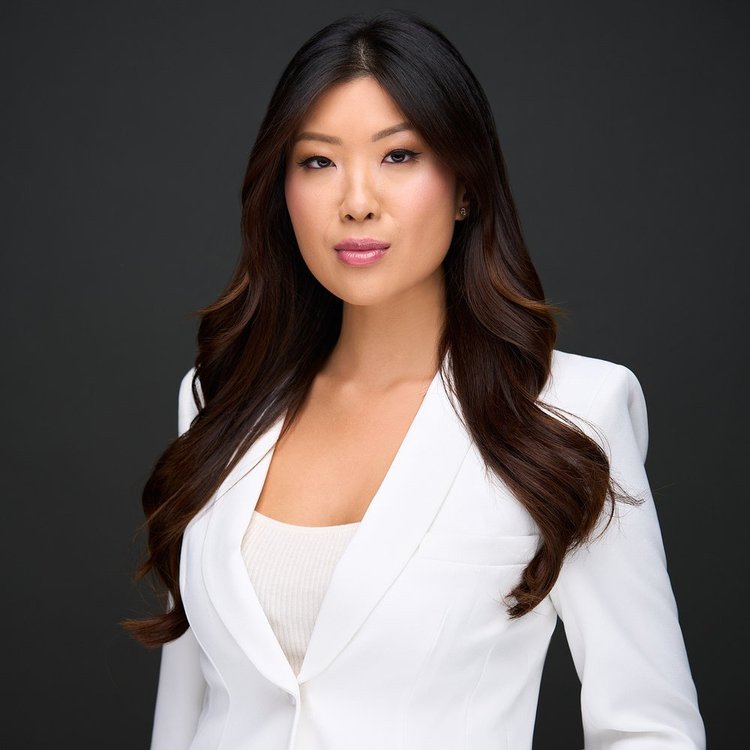 Woman with long dark hair in a white blazer on a dark background. ATX Headshots, Austin.