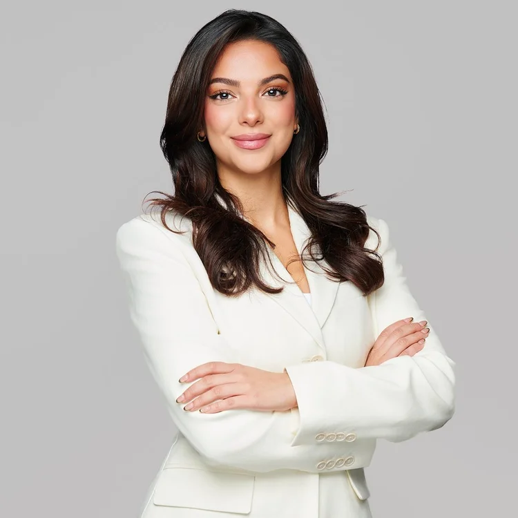 Portrait of a woman in a white jacket with arms folded, light background
