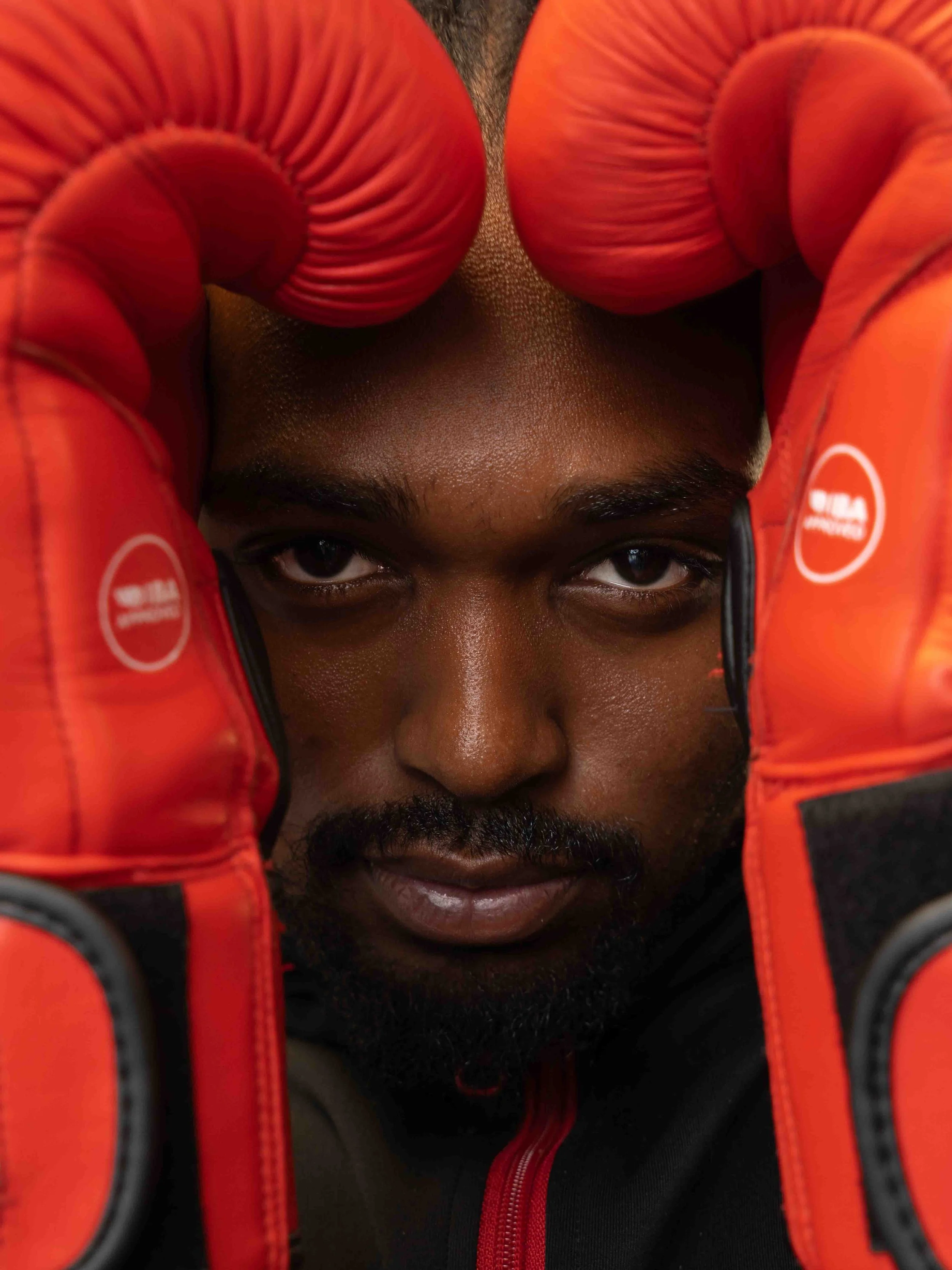 D’Andrej Felix, bronze medalist with Pinnacle Boxing Club in Belleville, captured in a portrait with red gloves and an intense post-fight expression.