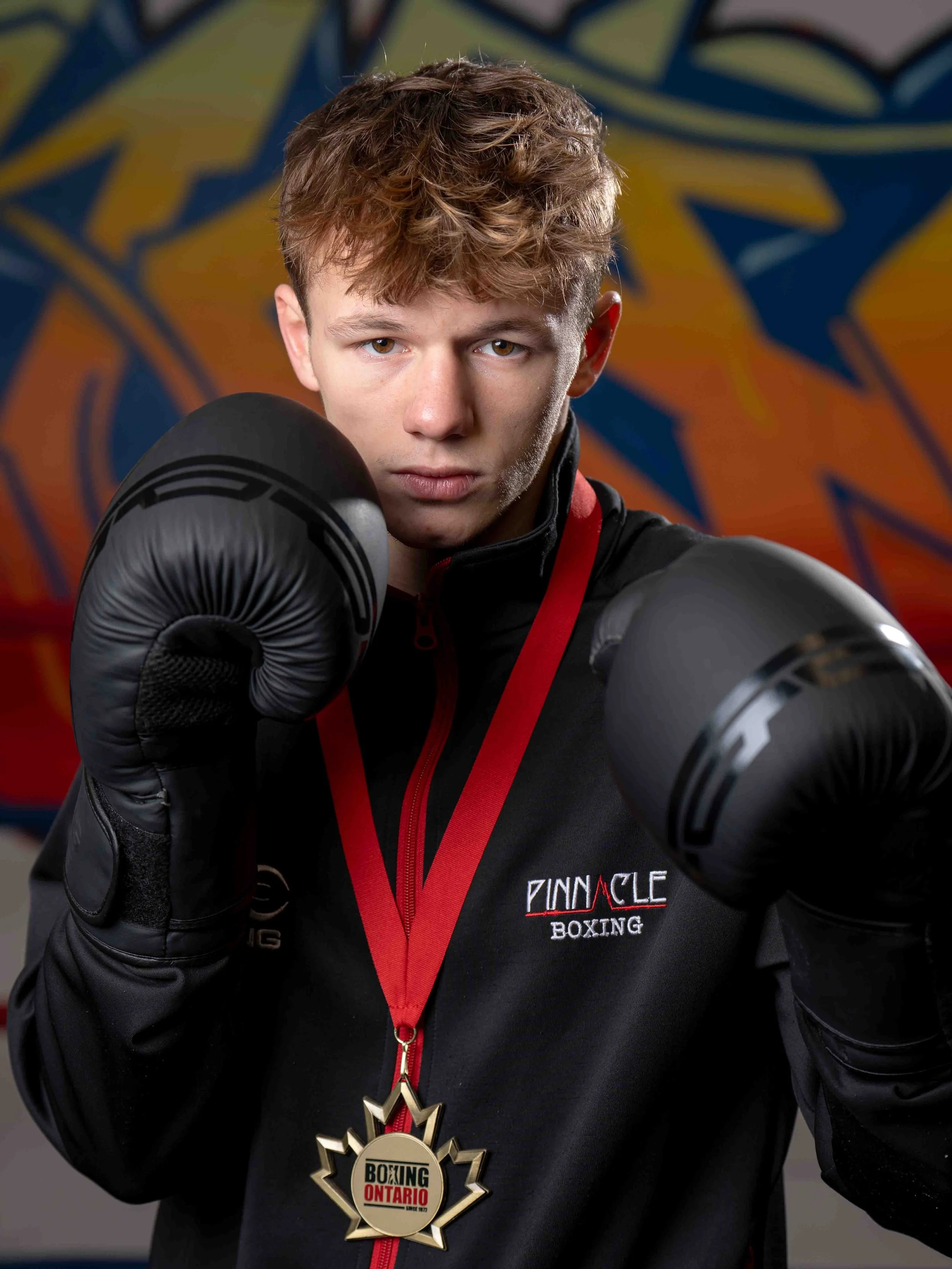 Avery Crawford, Golden Glove Champion from Pinnacle Boxing Belleville, poses confidently with gloves raised following her gold medal win at the provincial championships.