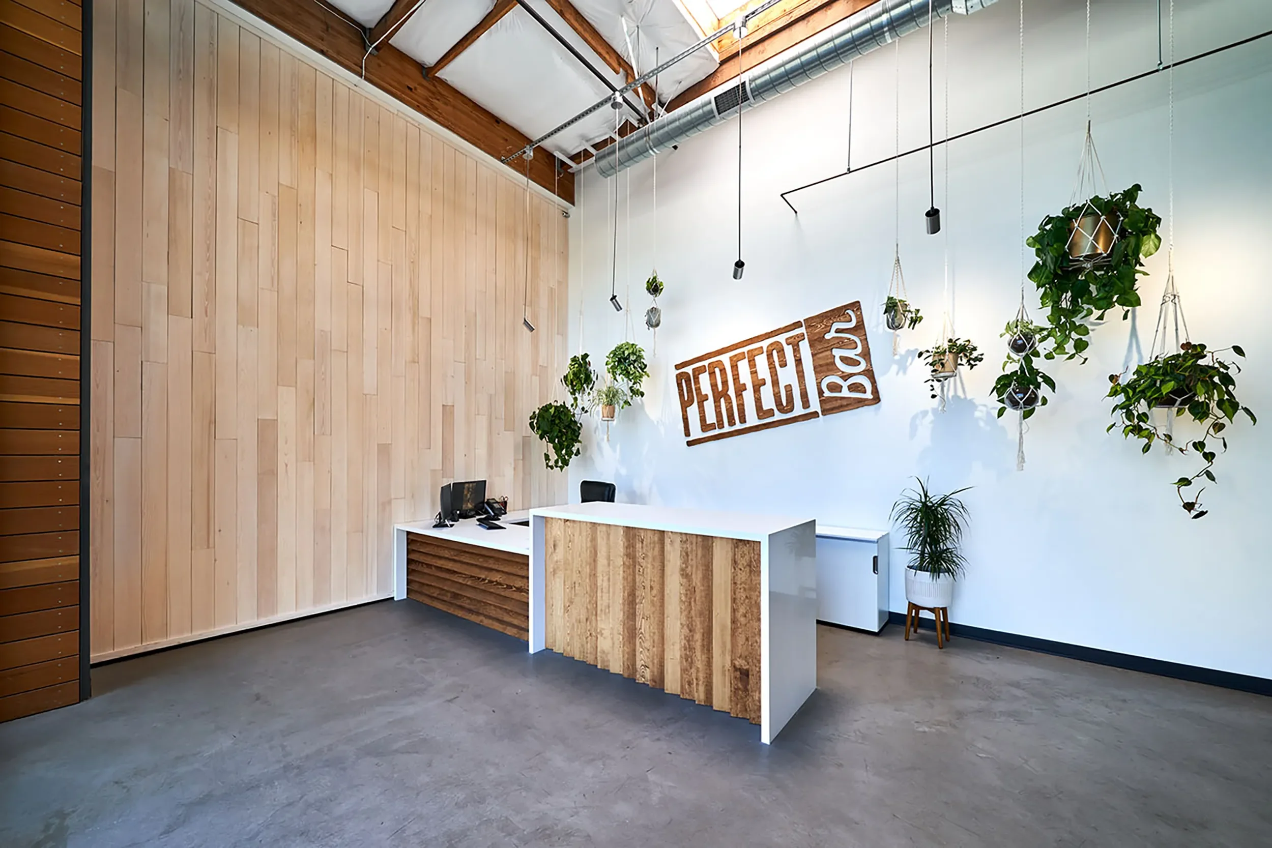 Custom reception desk against a vertical cedar wall in the Perfect Bar office lobby
