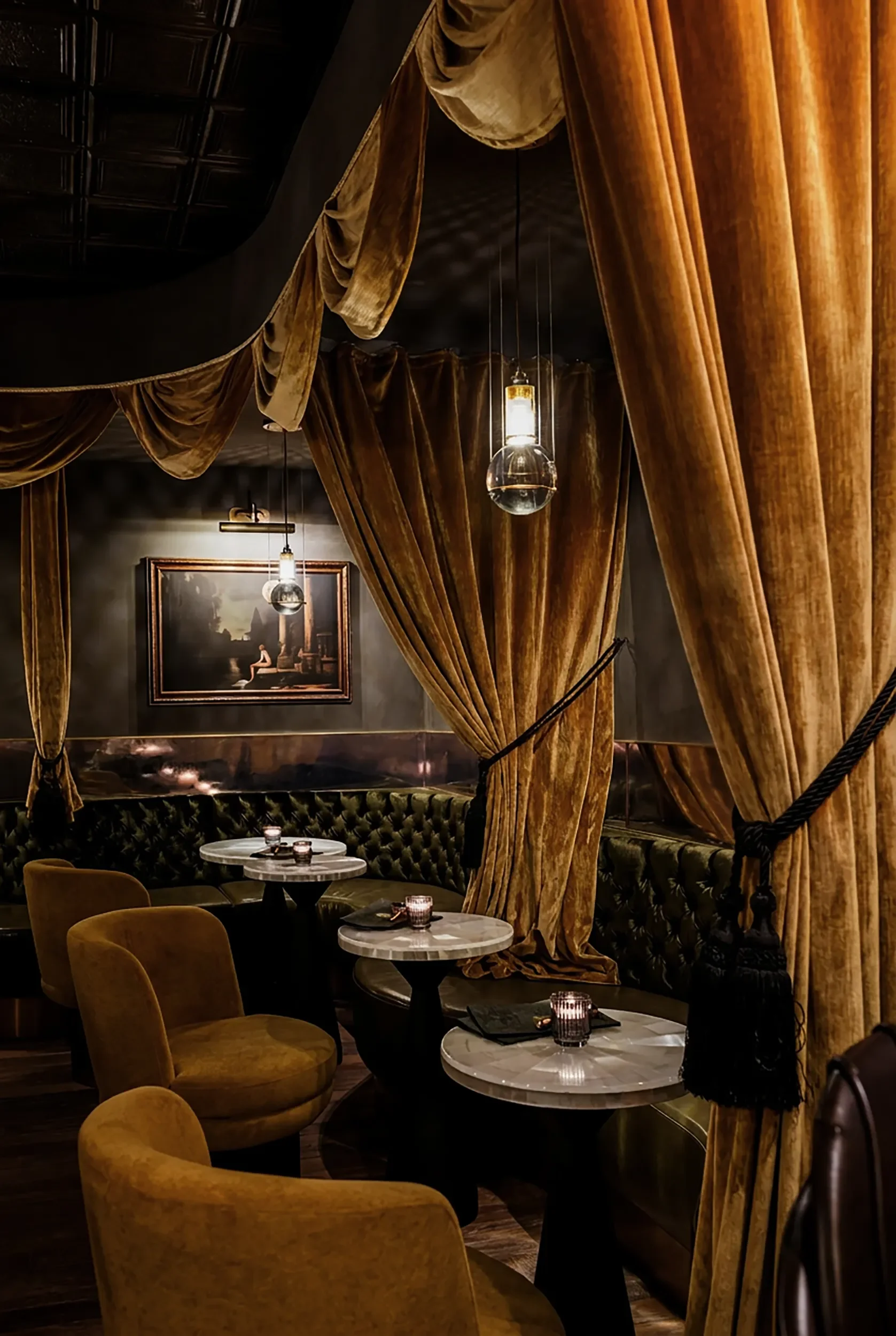 Velvet drapery and framed art over a curved banquette in the lounge at Anigma, Encinitas