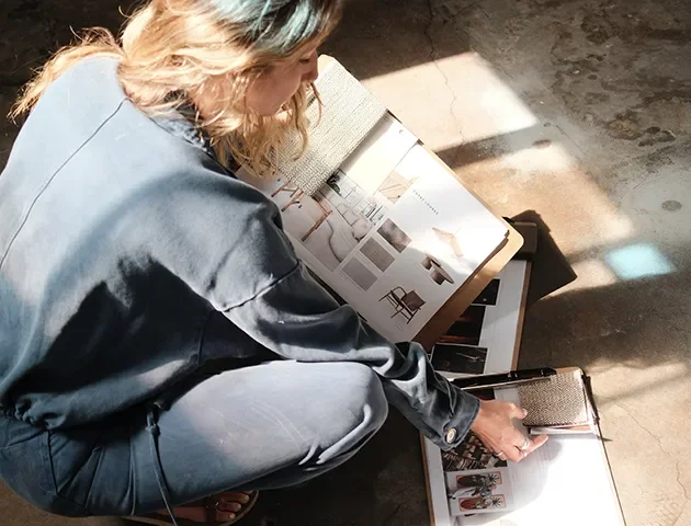 Tecture Studio designer seated on the floor reviewing a lookbook, materials and finish samples.