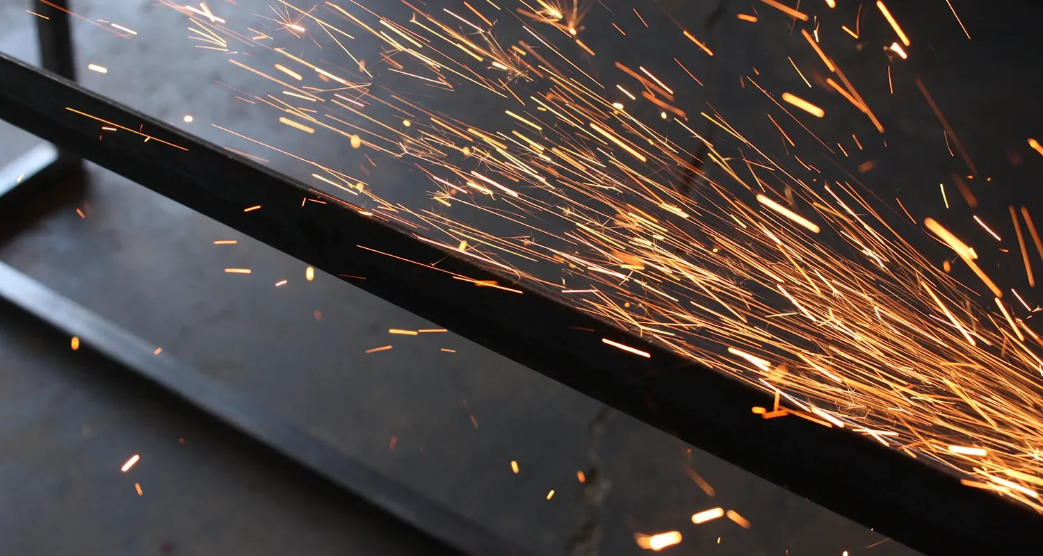 Sparks from a metal grinder cutting steel in the Tecture AF shop.
