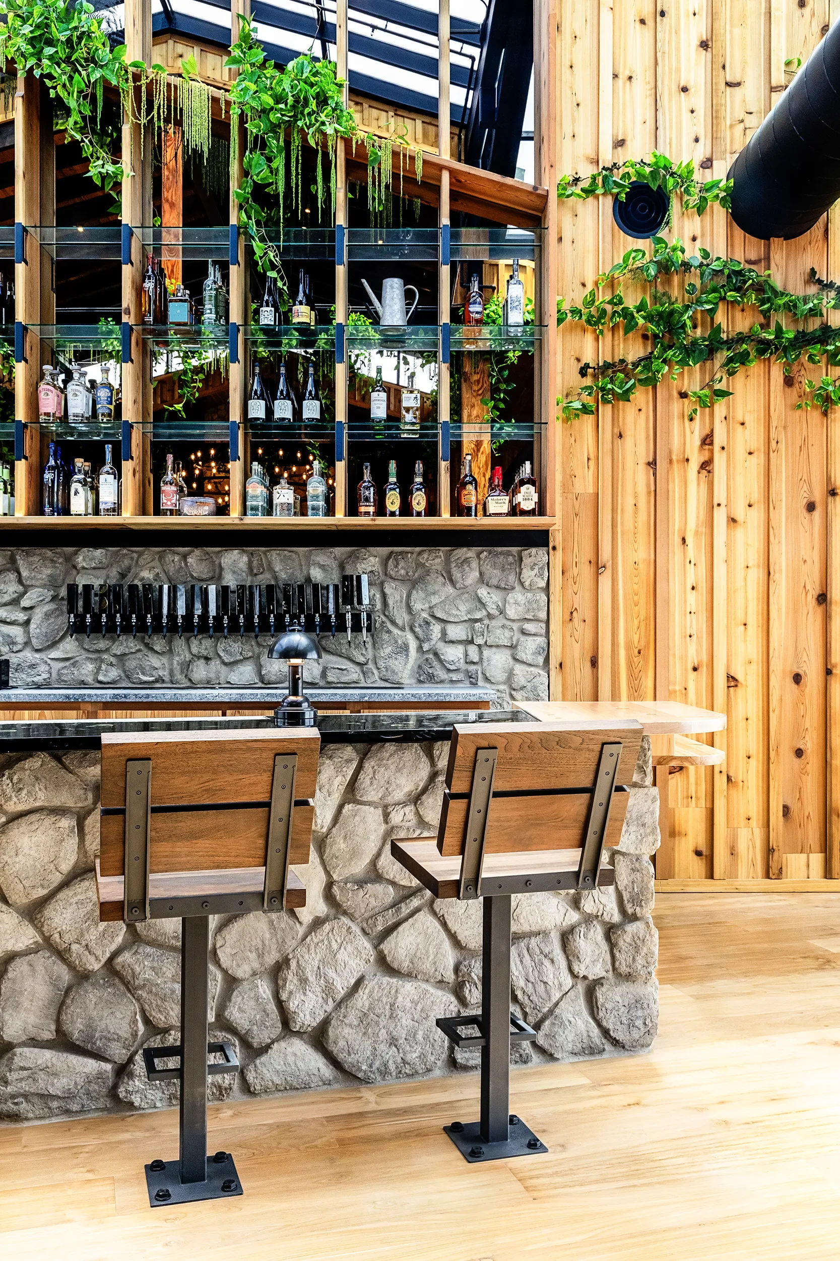 Stone-faced bar and custom dark resin counter top, with taps and bottle shelving at Fox Point Farms in Encinitas