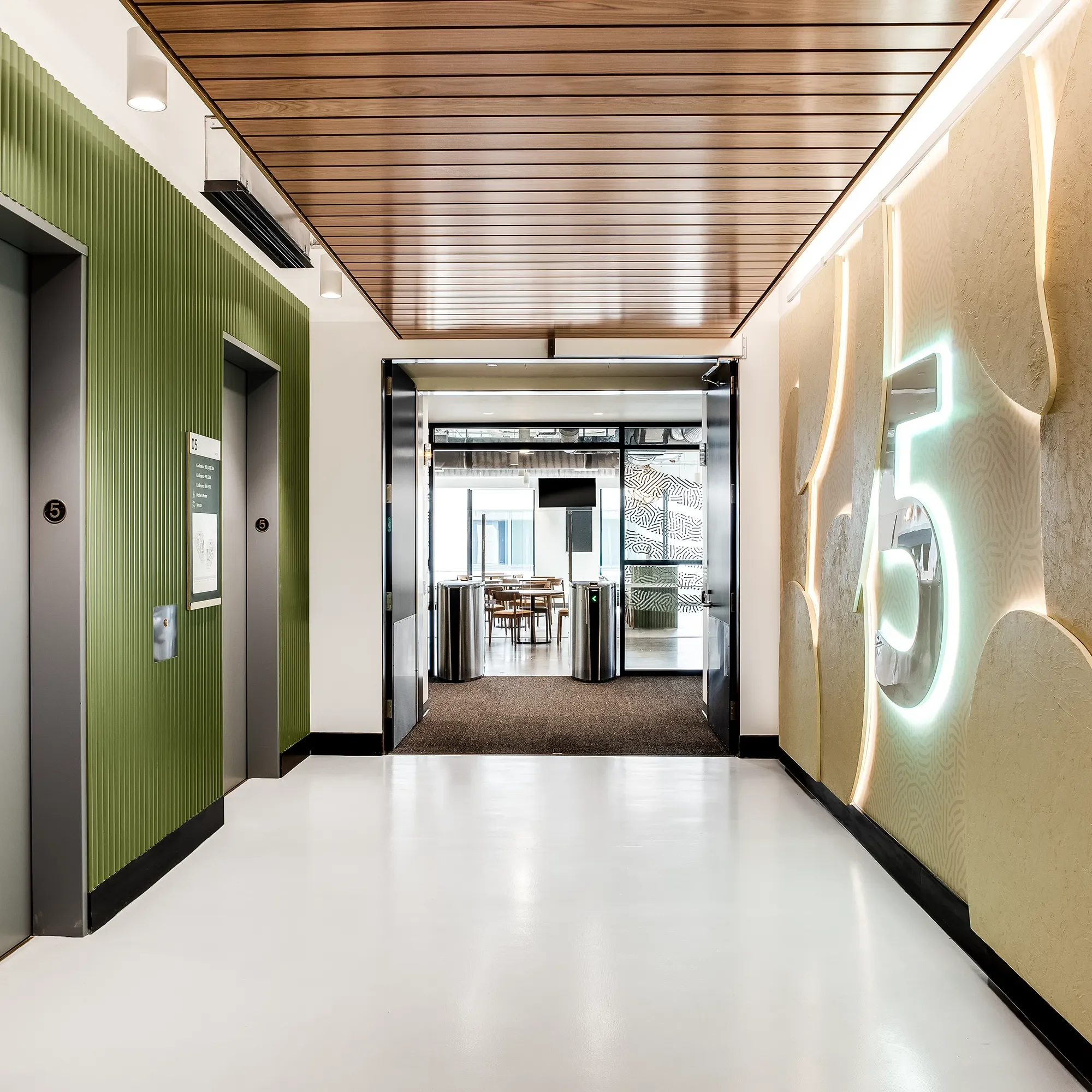 Illuminated floor number on a brass panel in a corridor with a wood slat ceiling system