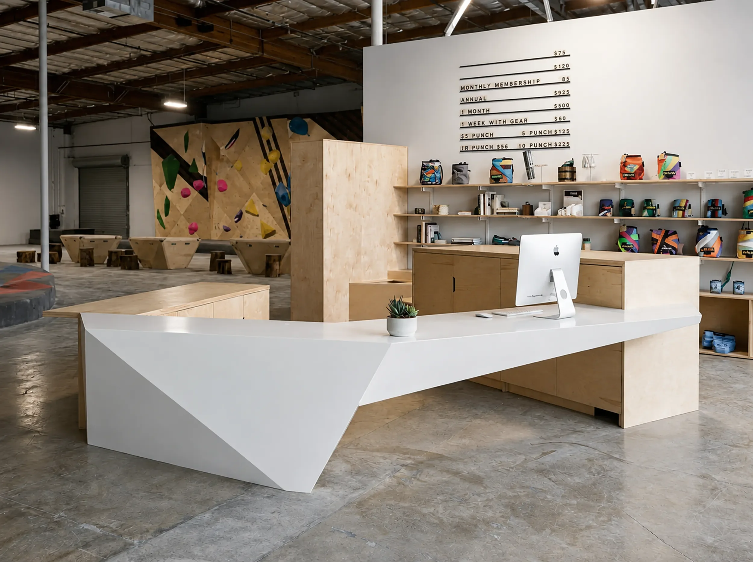 Angular white welcome desk and timber retail wall under exposed trusses at the Grotto in San Diego
