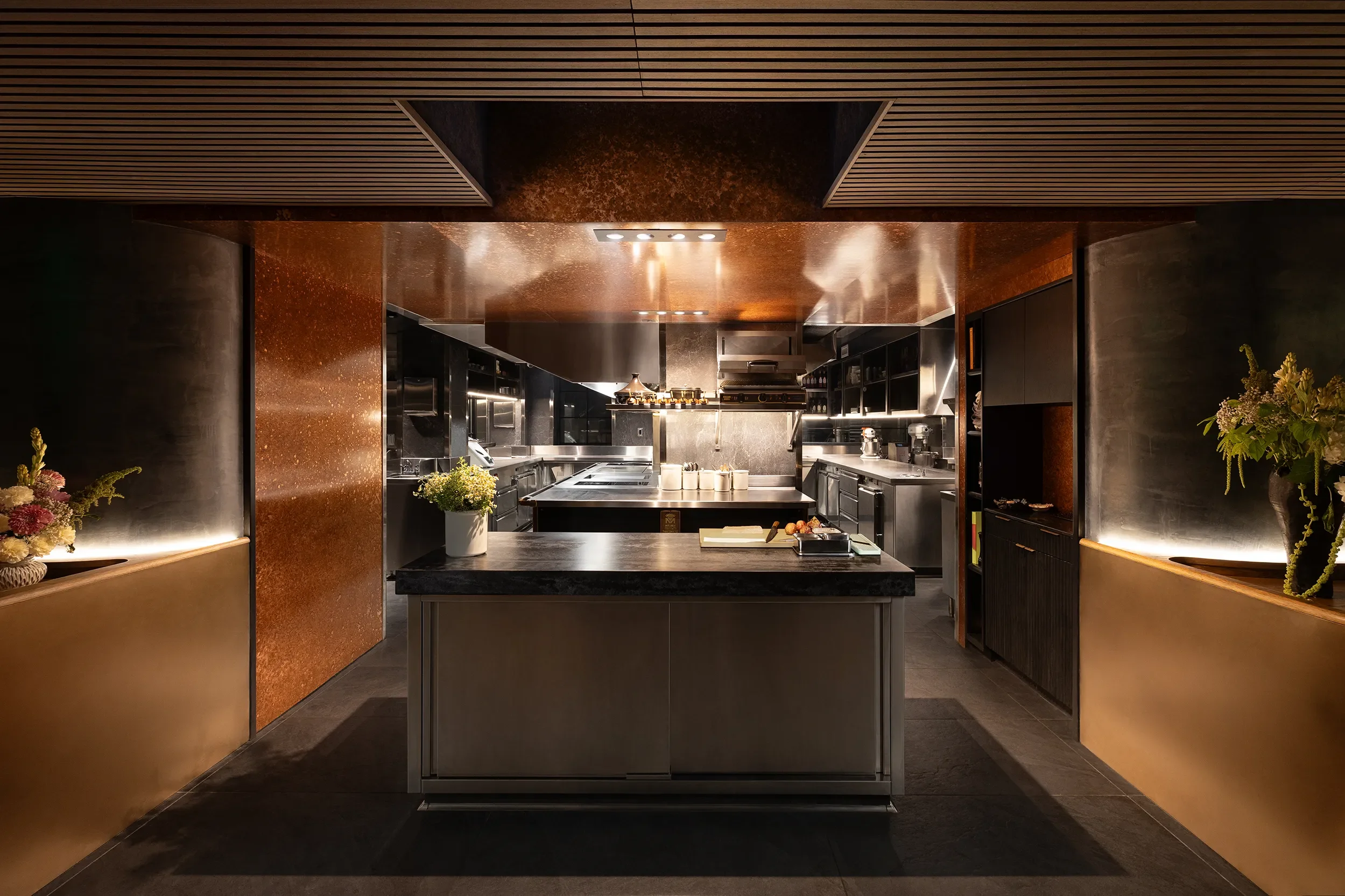 Open kitchen and chef's pass framed in warm metal cladding at Lucien in La Jolla