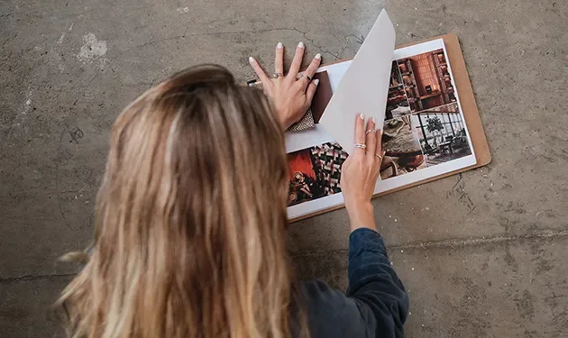 Tecture Studio designer reviewing a project lookbook and material samples on a concrete wall.