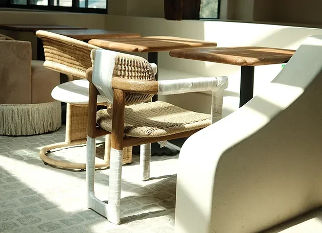 Woven dining chairs and a cream banquette placed in a sunlit dining room during a furniture install.