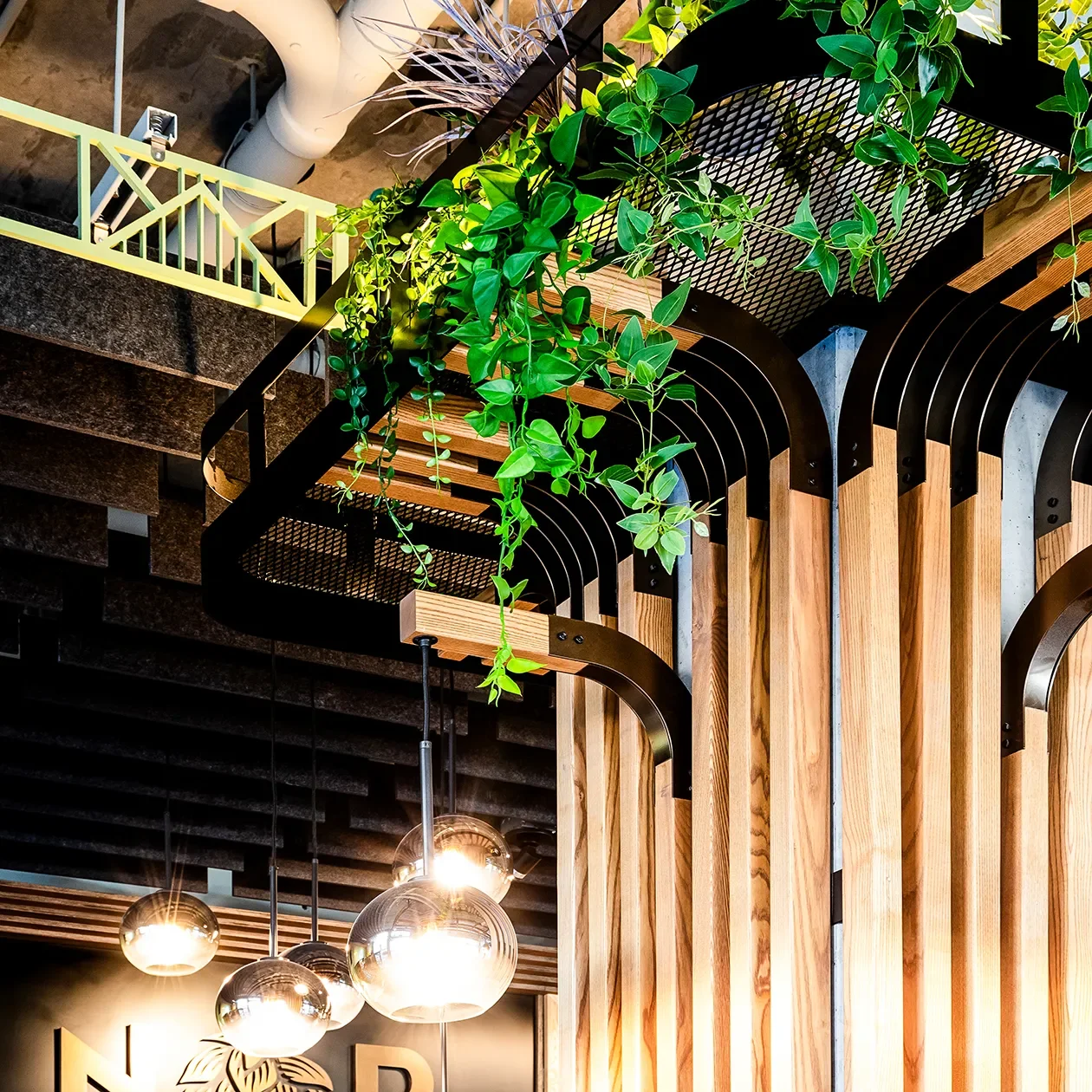 Black steel arch cladding and wood slats wrapping a column below an integrated custom planter