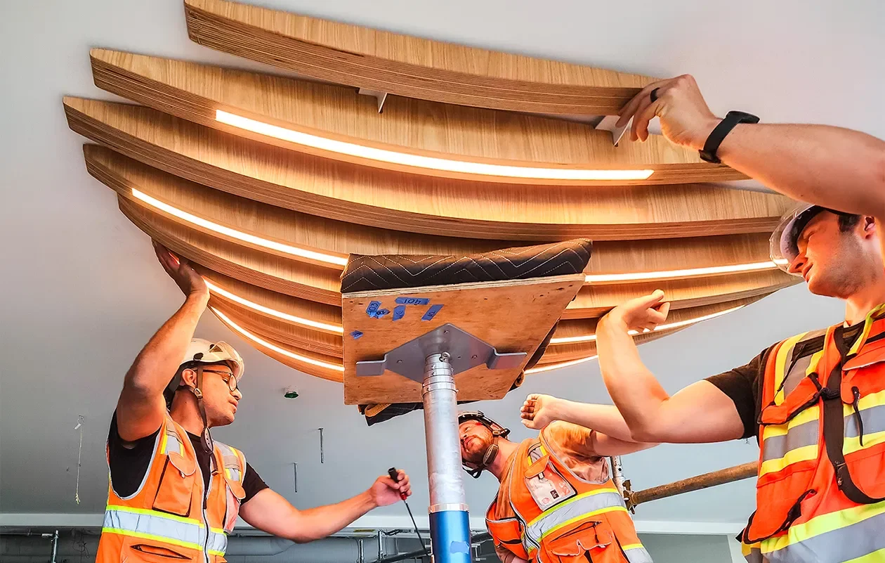 Tecture AF installation crew installing a large curved wood assembly on a job site.