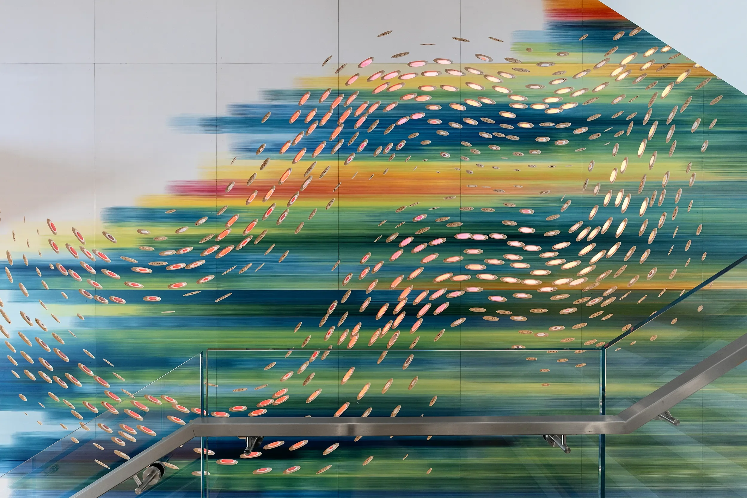 Detail of Convergence, a hand painted illuminated wall sculpture of banded color and a flock of metal forms in San Diego