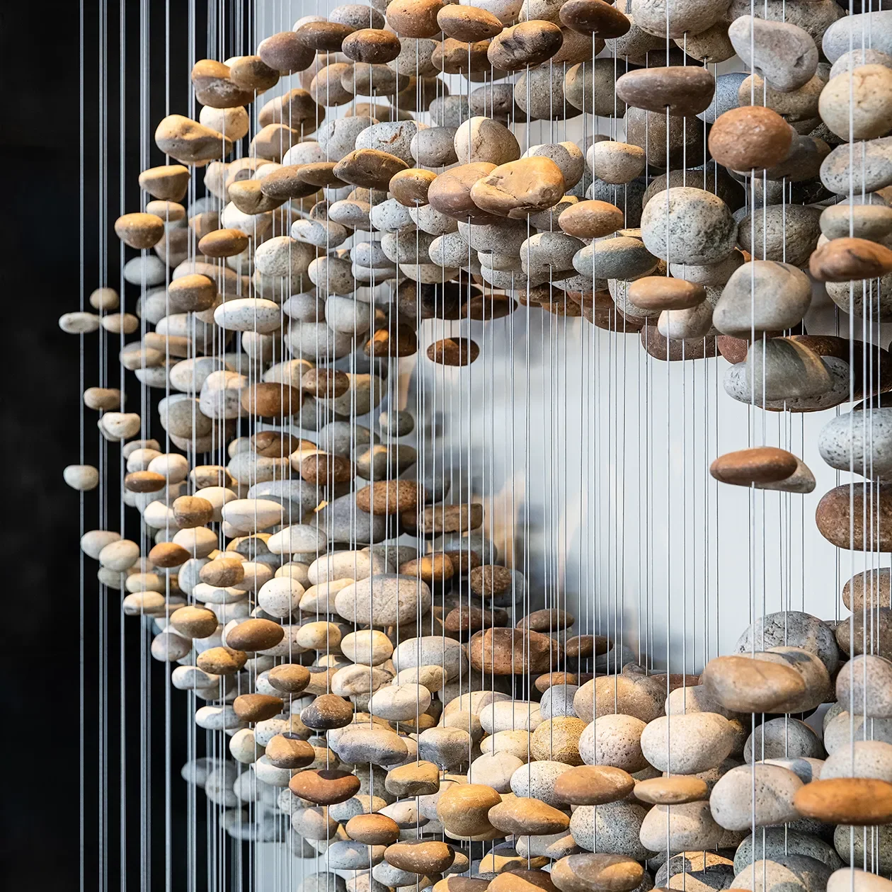 Beach stones hung on individual cables forming the underside of the Stone Flock sculpture