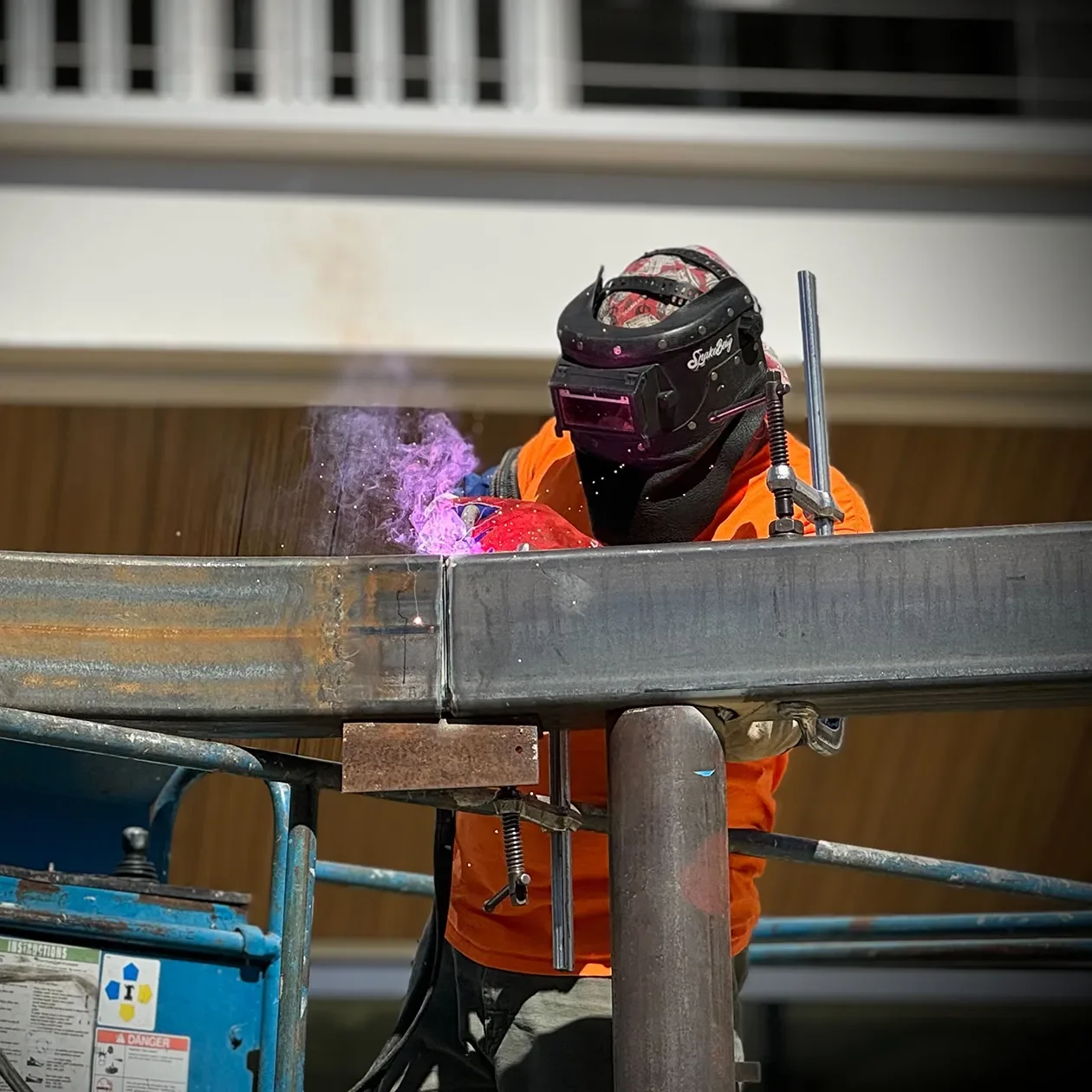 Welder joining a structural steel beam in the fabrication shop