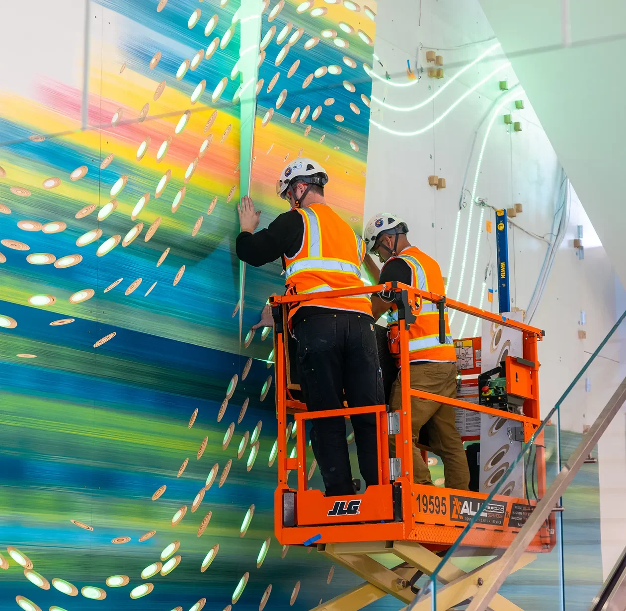 Install crew on a boom lift setting a large colorful feature wall on site in a commercial lobby space in San Diego.