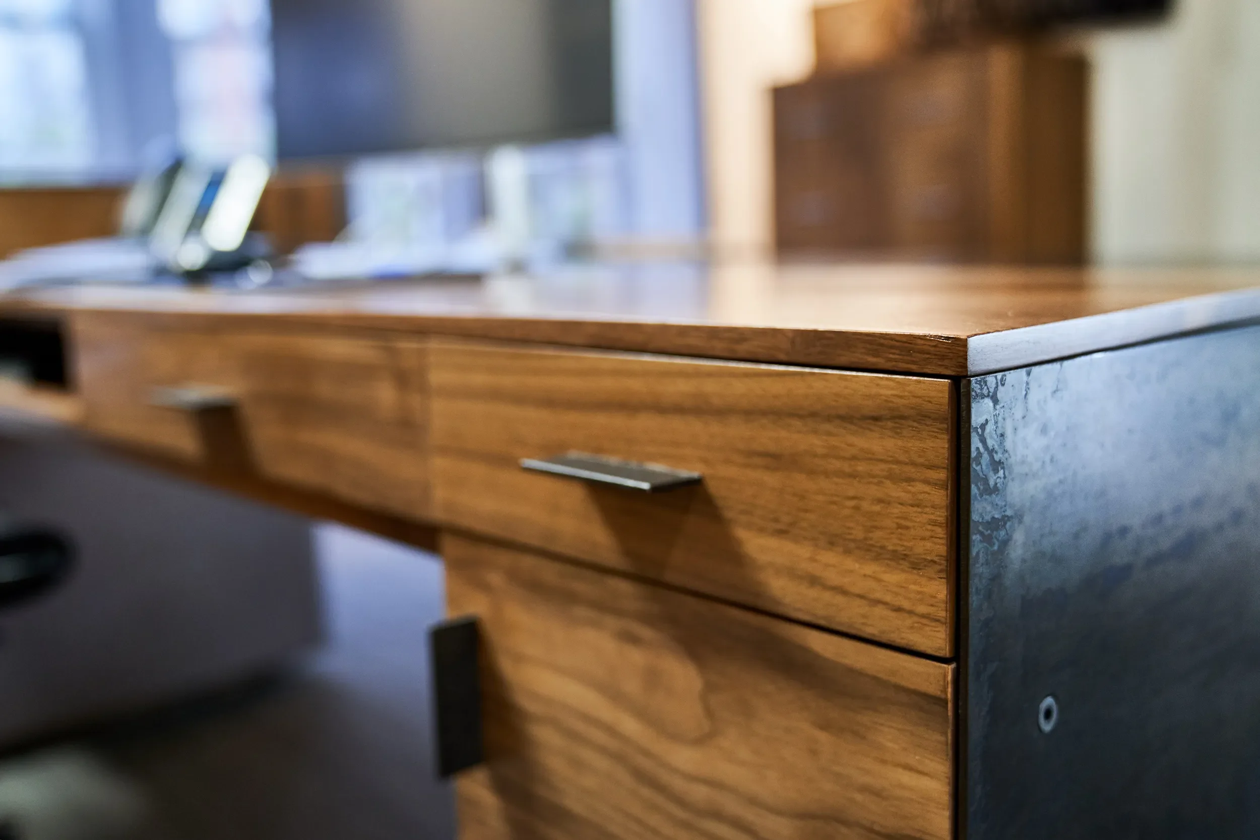 Close-up of a walnut desk drawer front with blackened steel hardware, J Street Office